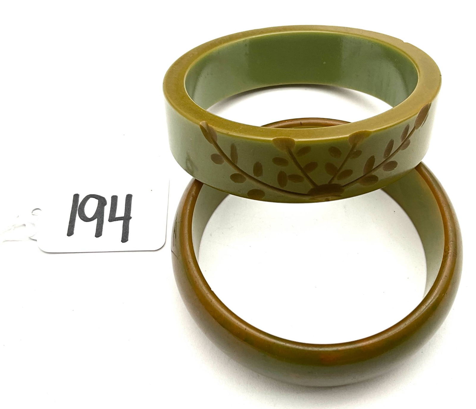 Carved Green Bakelite Bangles with Floral and Abstract Design: Vintage carved green Bakelite bangles, each measuring 2.5 inches in diameter. One bangle features an etched leaf motif, while the other displays smooth carving with a marbled appearance. Bakelite, an