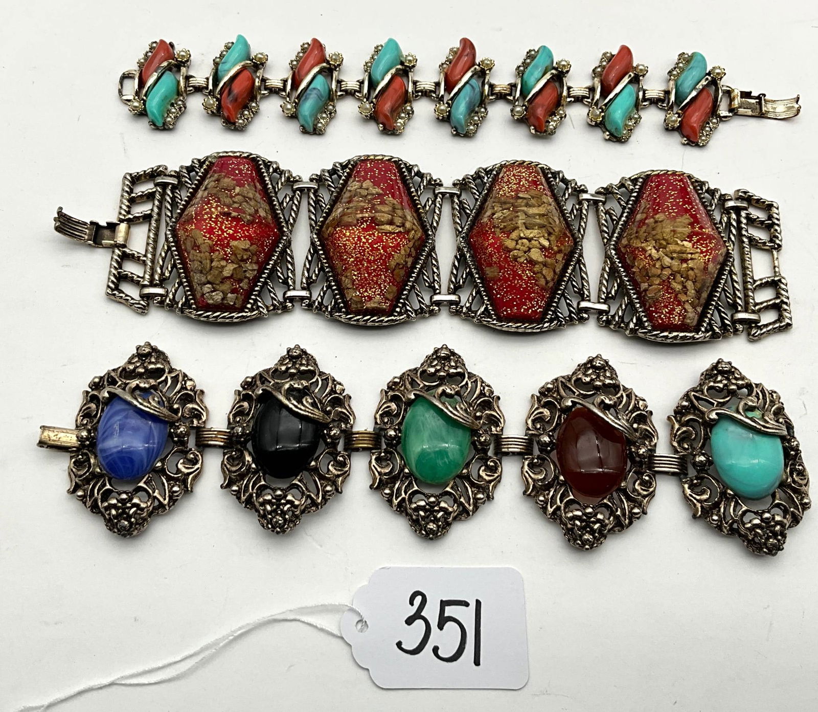 Three Decorative Stone-Inlaid Bracelets: Three stone-inlaid bracelets measuring approximately 7 inches long and 1 to 2 inches wide. The top bracelet is adorned with alternating turquoise and coral-colored stones, enclosed in textured metalwo
