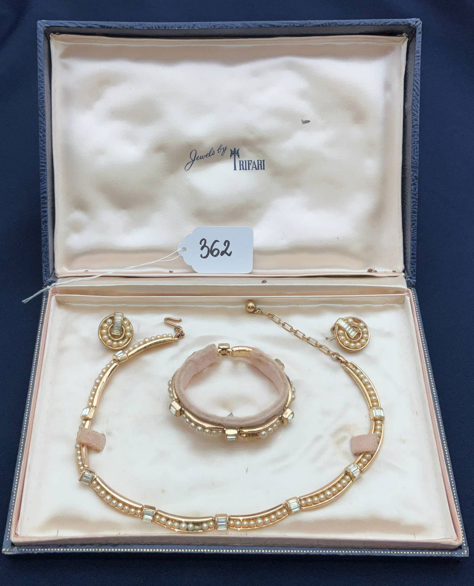 Trifari Faux Pearl and Rhinestone Jewelry Set with Necklace, Bracelet, and Earrings: Jewelry set marked "Trifari," featuring a gold-tone metal design adorned with faux pearls and clear rhinestones. Includes a matching bracelet, necklace, and clip-on earrings. The set is presented in a