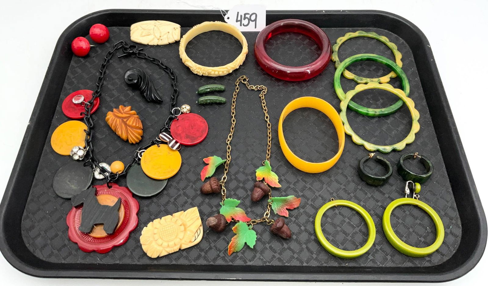 Vintage Bakelite Jewelry Including Bracelets and Necklaces: Various vintage Bakelite jewelry items, comprising a selection of bangles, necklaces, brooches, and earrings. Highlights include a carved dog pendant on a black chain, a chain necklace with colorful l
