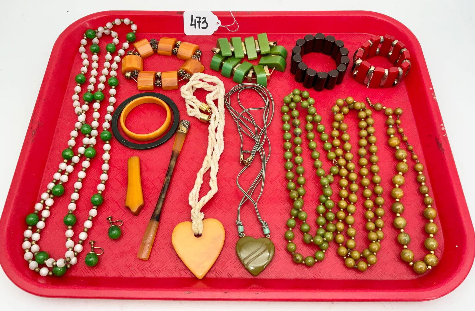 Vintage Bakelite Jewelry in Various Styles and Colors: Vintage Bakelite jewelry, showcasing necklaces, bracelets, earrings, and bangles in vibrant tones of green, orange, and yellow. Items include multi-strand necklaces, sculptural pendants, and geometric