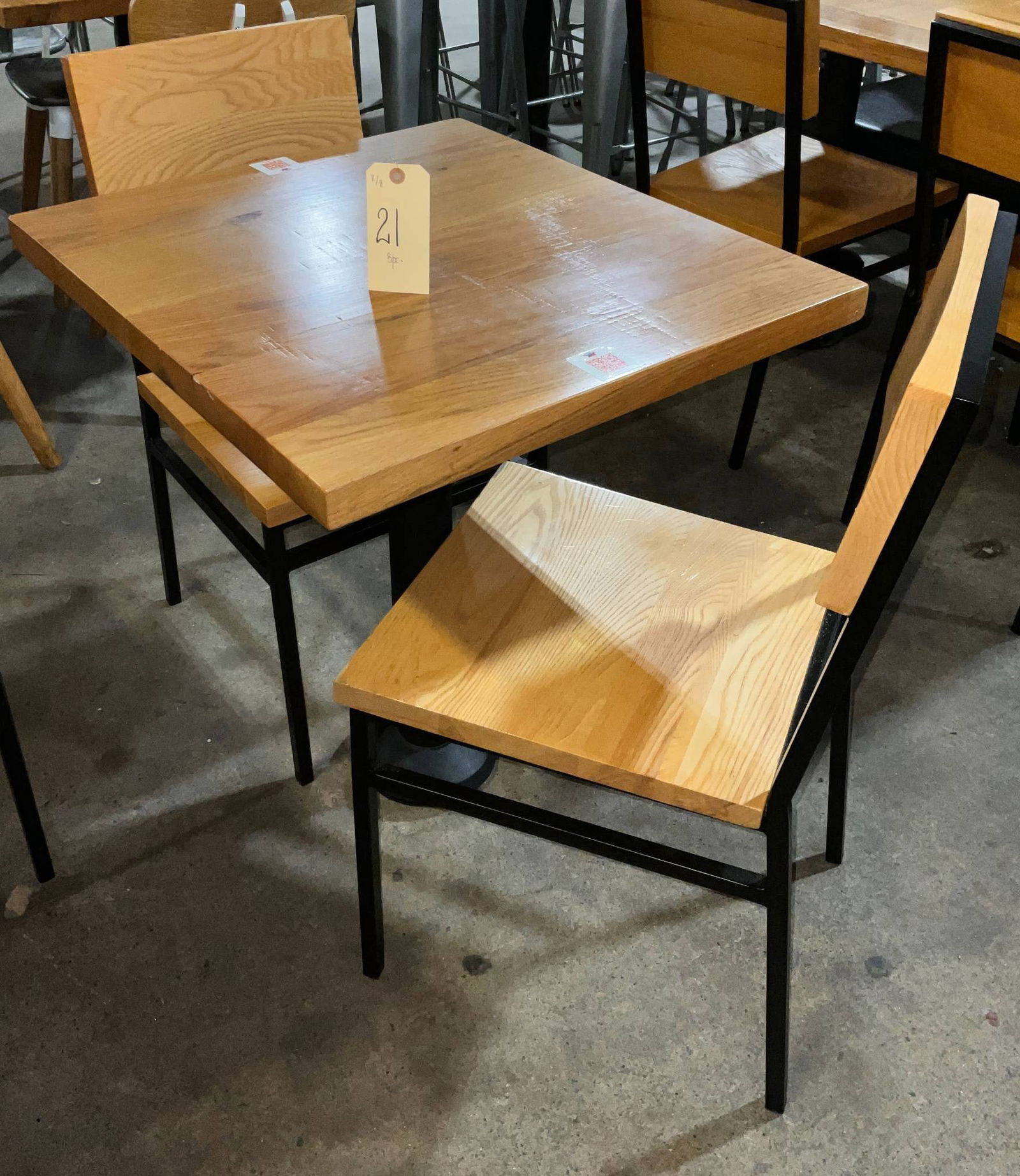 Wooden Table With Metal Base and Two Matching Chairs: Wooden table featuring a metal base designed for floor mounting, accompanied by two matching chairs. The table measures 24 x 27 x 29 inches tall. This set is suitable for residential or commercial use