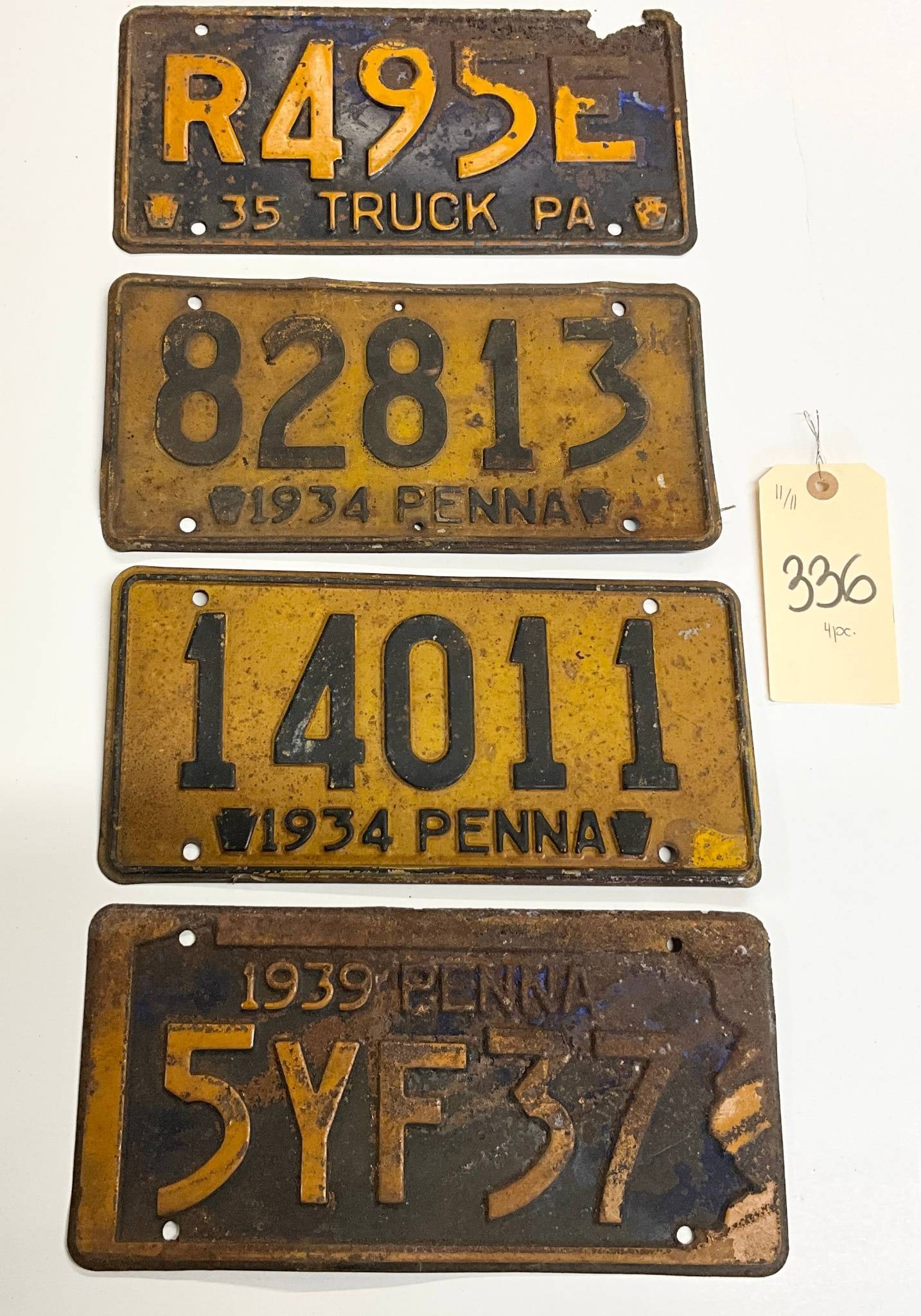 4 Vintage Pennsylvania License Plates from 1934, 1935, and 1939: Four vintage Pennsylvania license plates. One plate is marked 'R49SE 35 TRUCK PA,' indicating a 1935 truck plate. Two plates are labeled '1934 PENNA,' with serial numbers '82813' and '14011.' The four
