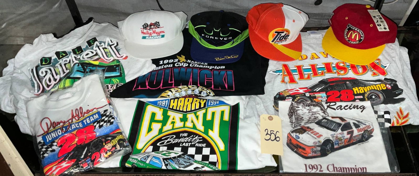 NASCAR-Themed T-Shirts and Hats Featuring Drivers and Sponsors: NASCAR-themed apparel, including printed T-shirts in medium and large sizes and a selection of hats. The T-shirts feature designs with popular drivers such as Harry Gant, Dale Jarrett, and Davey Allis