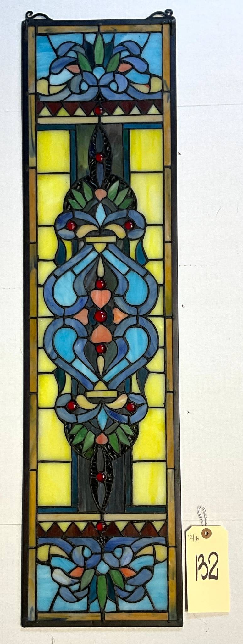 Stained Glass Panel with Geometric and Floral Motifs: Rectangular stained glass panel measuring 9 inches by 35 inches. Constructed with leaded glass, it features a central geometric and floral motif in vibrant hues of blue, red, green, and yellow. The in