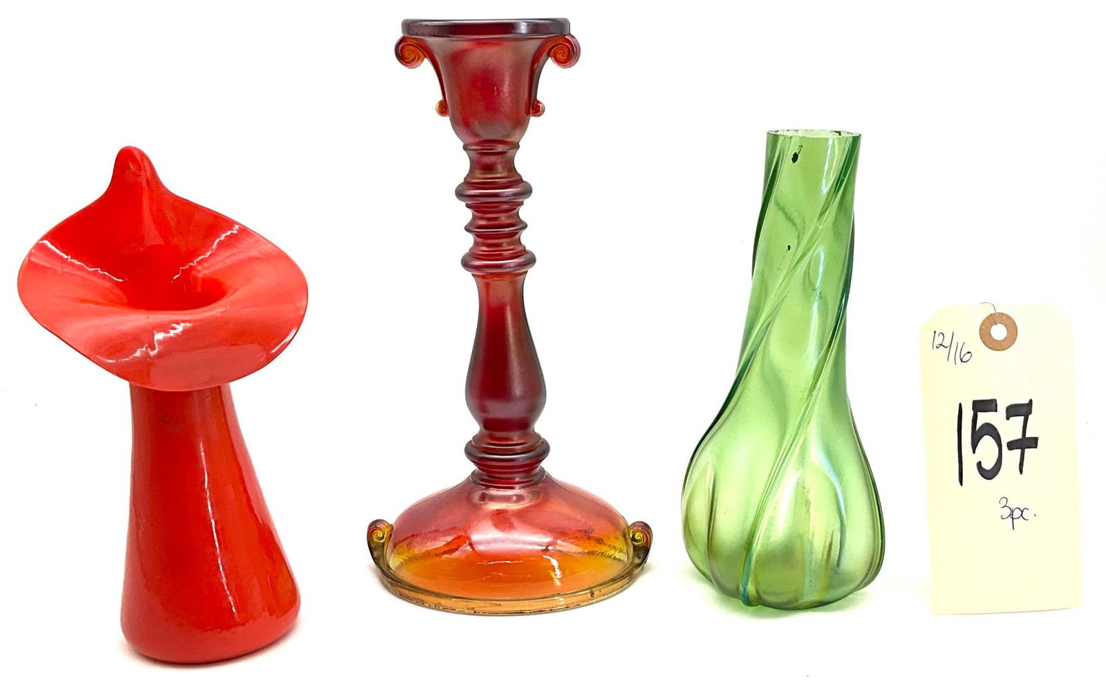 Red Jack-in-the-Pulpit Vase, Green Swirl Vase, and Pressed Glass Candlestick, 7 to 8.75 Inches Tall: Three glass decorative items, including a red Jack-in-the-Pulpit vase marked "Czechoslovakia", a green vase with a twisted swirl design, and a pressed glass candlestick featuring a red-to-amber gradie