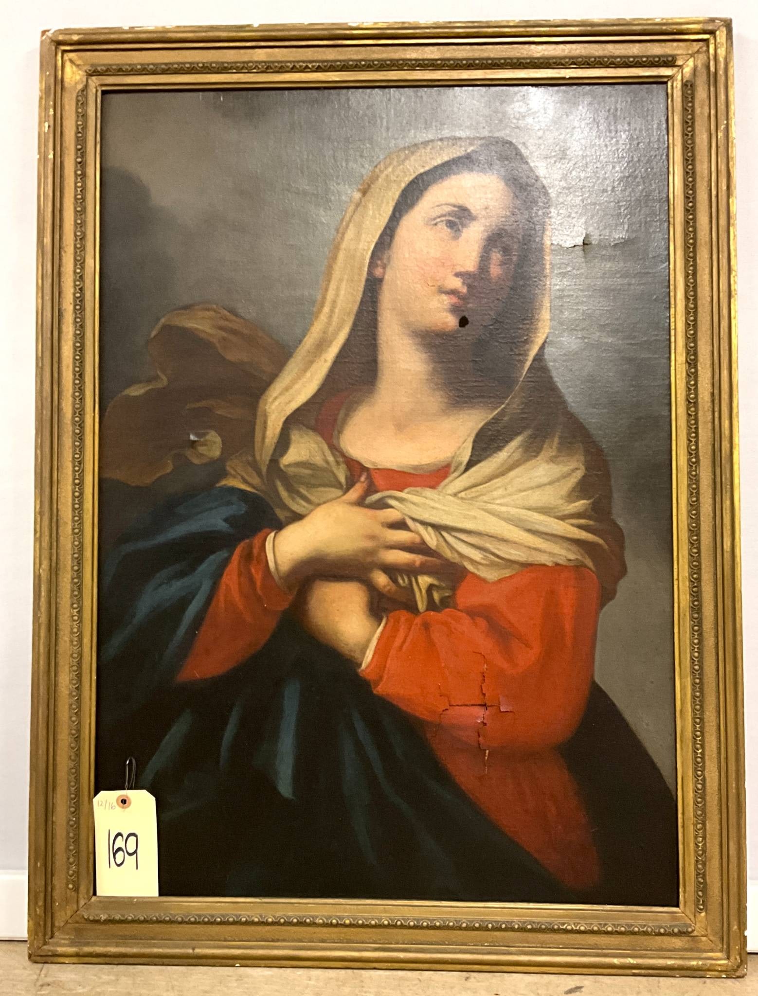 Vintage Painting on Canvas Depicting the Madonna in Ornate Frame, as is: Vintage Oil painting on canvas featuring the Madonna in a contemplative pose, her hands crossed over her chest. The subject is draped in traditional red, blue, and cream garments. The painting is hous