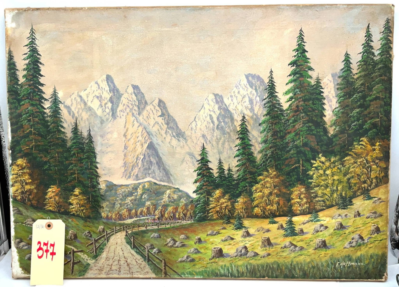 Oil Painting on Canvas by F. Hoffmann Depicting the Alps, 20 x 27 Inches: Oil painting on canvas signed by artist F. Hoffmann, measuring 20 x 27 inches. The artwork depicts a serene alpine landscape featuring towering snow-covered peaks, lush green conifer trees, a winding 