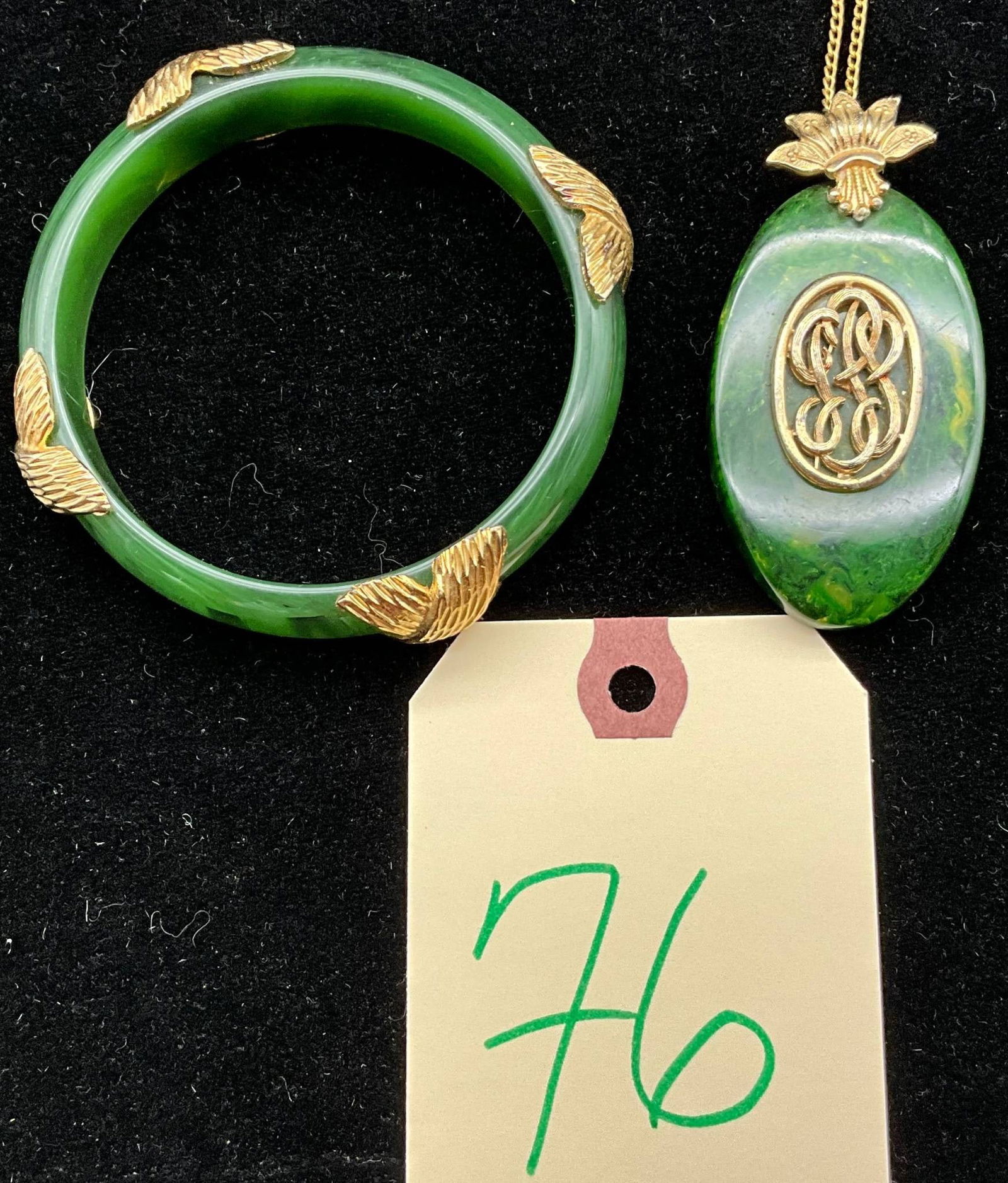 Green Marbled Bakelite Necklace and Bangle with Gold-Tone Accents: Green marbled bakelite necklace featuring an oval pendant with a gold-tone floral and filigree centerpiece. Suspended from a 24-inch gold-tone chain. Accompanied by a matching green marbled bakelite 2