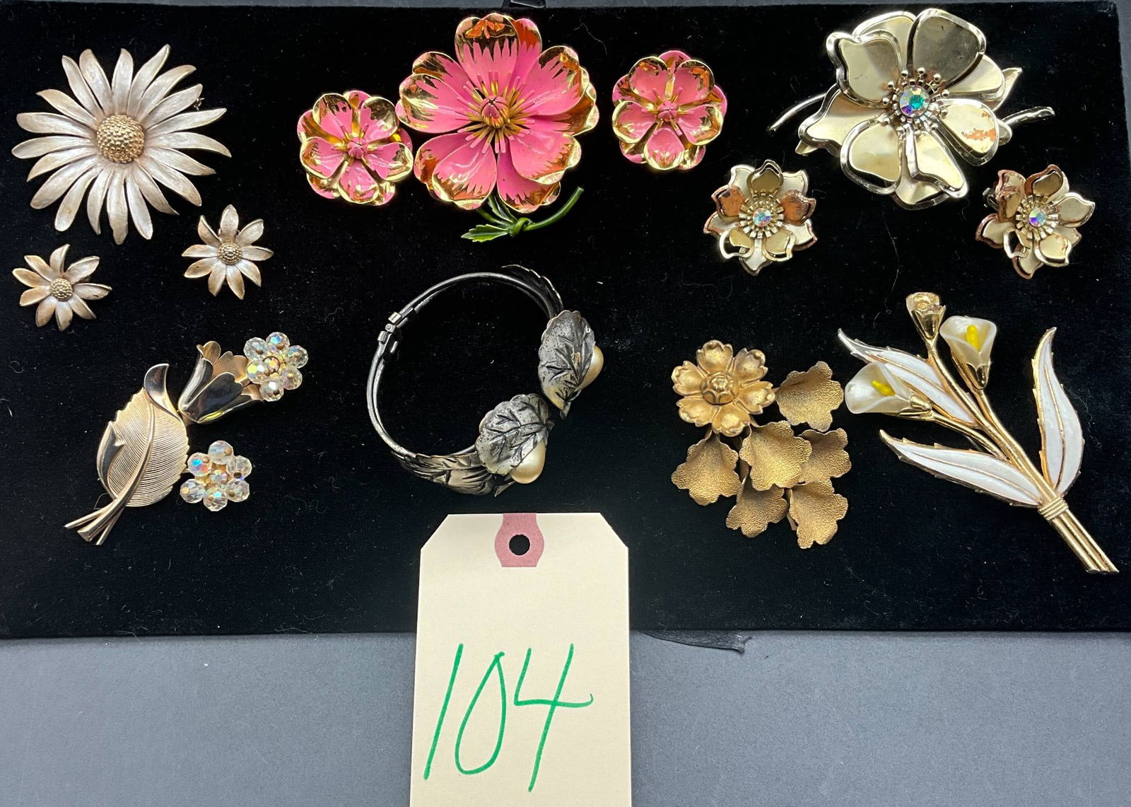 Floral-Themed Vintage Pins and Earring Sets: Pins and coordinating earring sets depicting various floral designs, including daisies, calla lilies, and other blossoms. Materials include metal, faux pearls, enamel, and aurora borealis rhinestones.