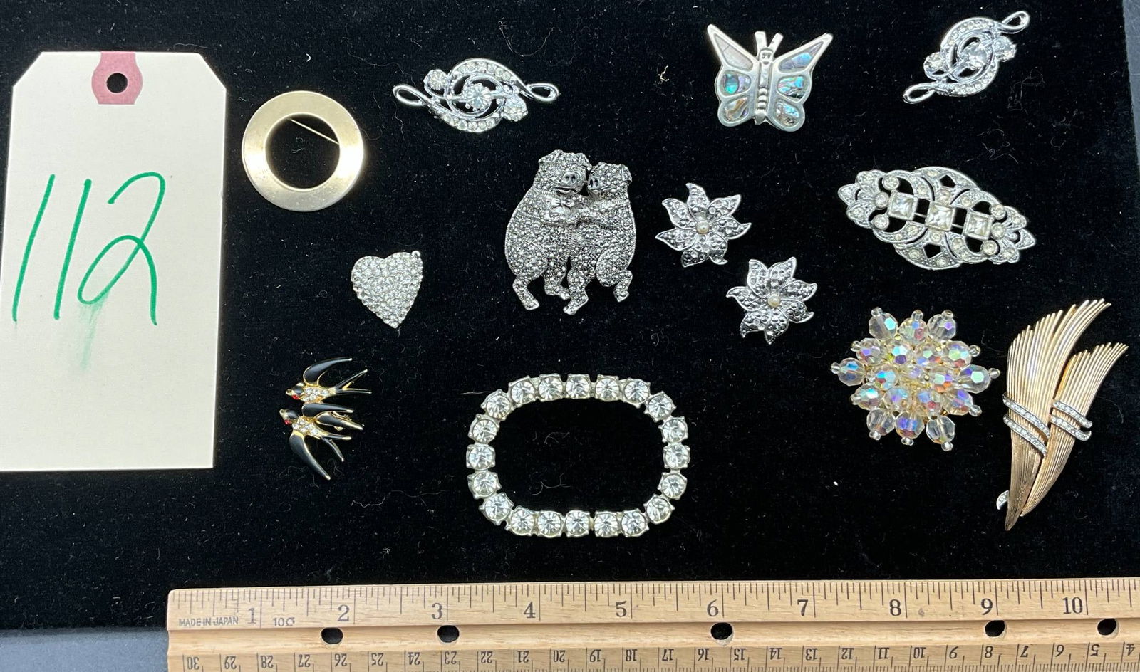 Brooches and Accessories Featuring Trifari, Marcasite, and Abalone Designs: Brooches and accessories, including a gold-tone Trifari leaf brooch with engraved hallmark, a marcasite heart brooch, an abalone butterfly piece, a dancing pigs brooch with intricate detailing, two bi