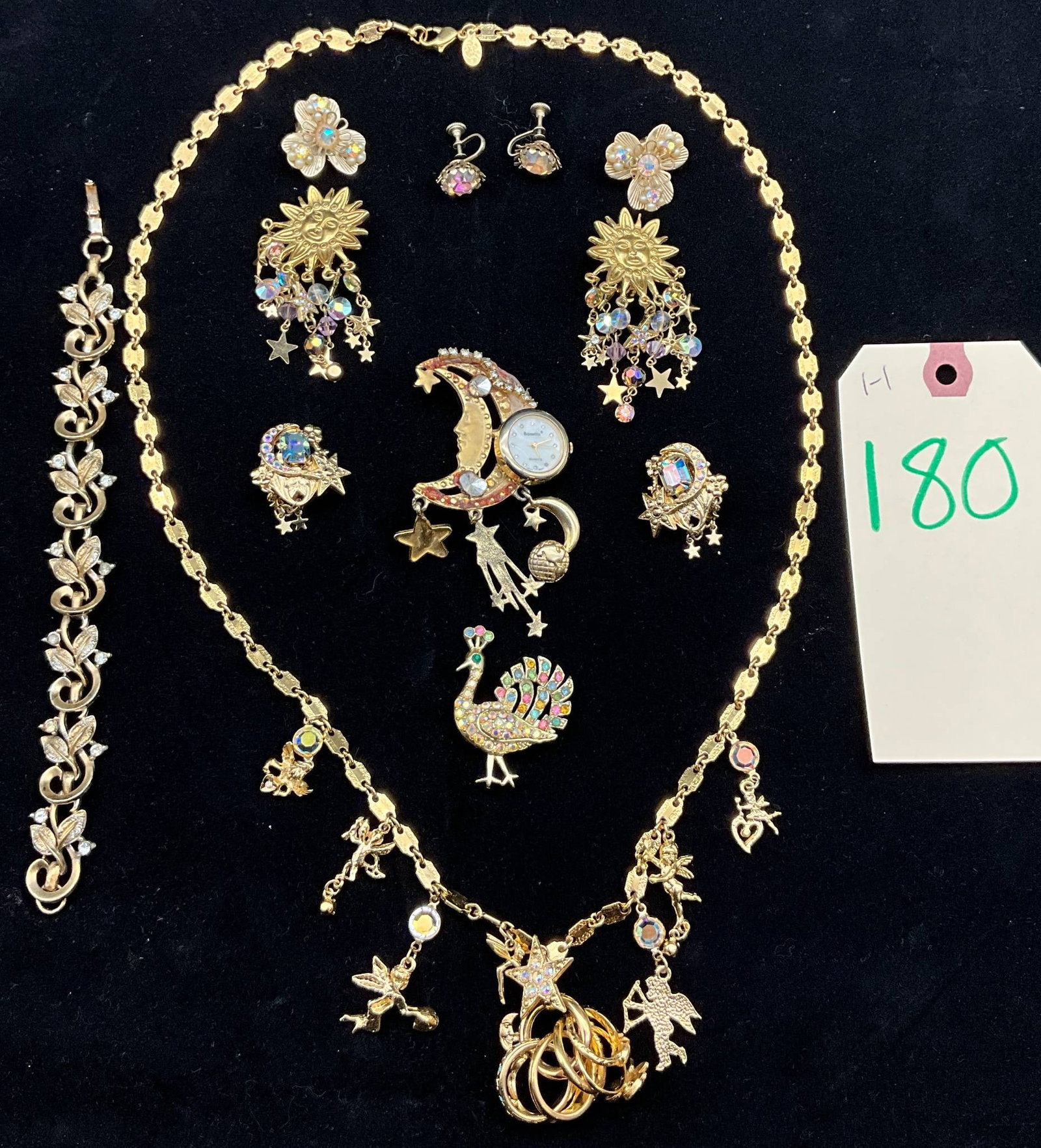 Gold Toned Jewelry Set Featuring Necklace, Bracelet, and Kirks Folly Pieces: Gold-toned jewelry set including an 8-inch bracelet with a detailed floral and vine design and a 28-inch necklace featuring whimsical charms, such as fairies, moons, stars, and hearts. The collection