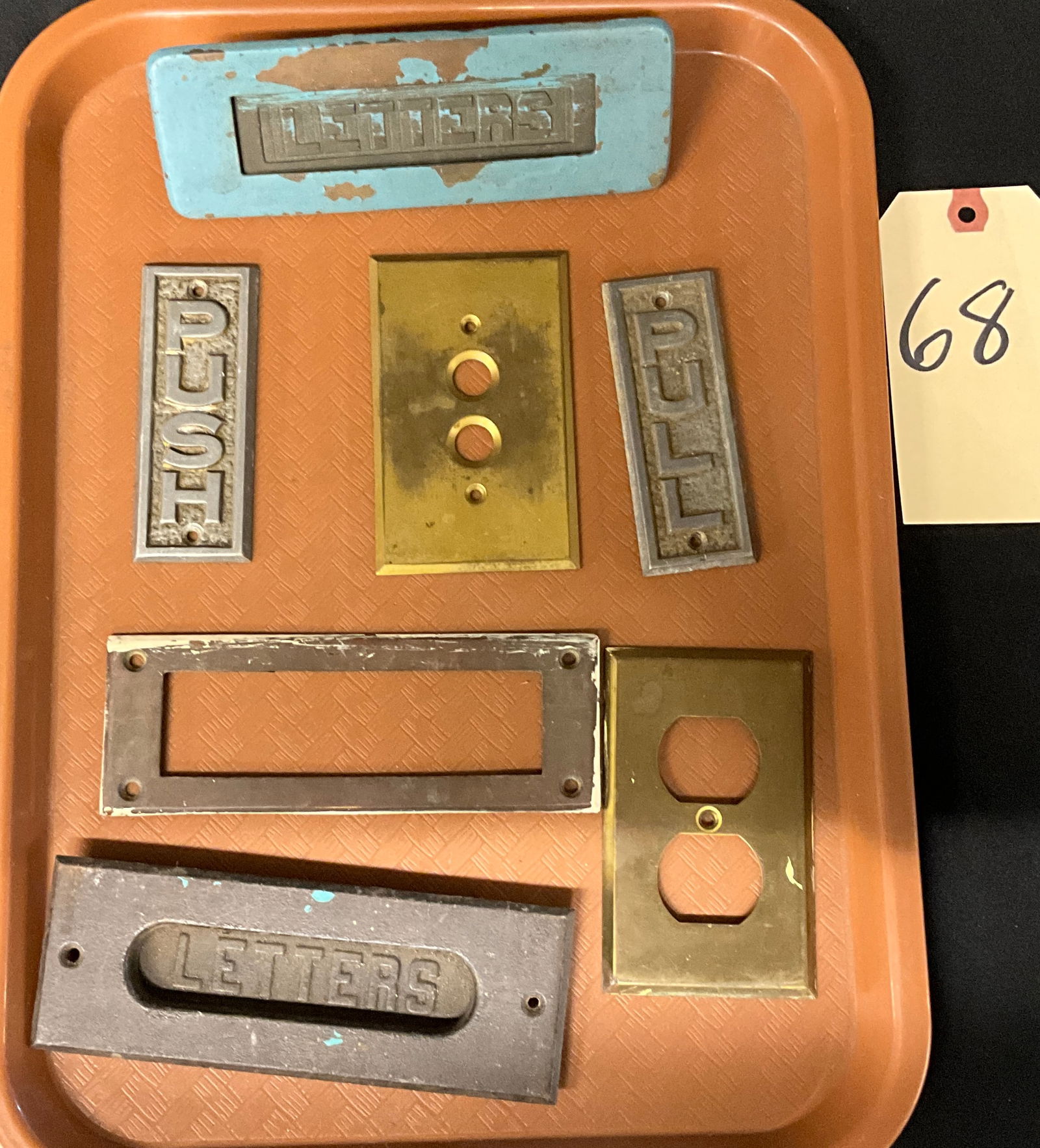 Collection of Antique and Vintage Architectural Salvage Hardware: A collection of antique and vintage architectural salvage hardware, primarily cast iron and brass, displayed on a modern serving tray. The lot includes two heavy mail slot covers, both featuring the r