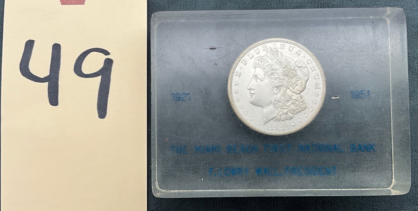 US 1921 Morgan Silver Dollar Paperweight, Silver, KM-110: KM-110. Designer: George T. Morgan. Philadelphia Mint. Morgan obverse / Eagle reverse. This 1921 Morgan silver dollar is embedded in a clear rectangular acrylic commemorative paperweight. The acrylic