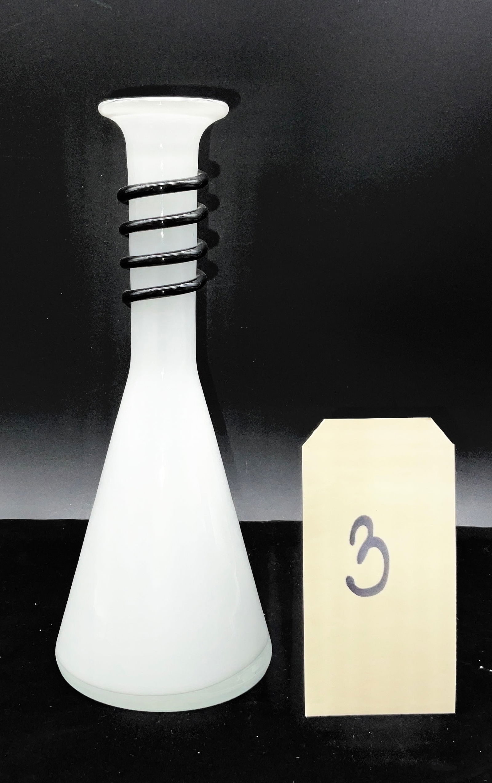 Mid-Century Modern Murano Style White Art Glass Vase with Black Coil: This modernist sculptural vase is crafted from opaque white art glass in the style of mid-century Murano makers. The form features a broad conical base tapering to a cylindrical neck embellished with