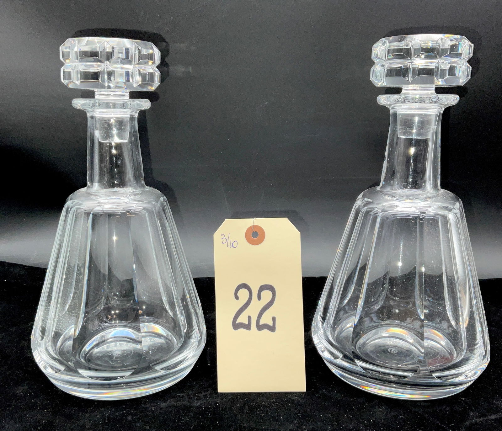 Pair of Baccarat France Talleyrand Pattern Cut Crystal Decanters with Stoppers: This pair of Baccarat clear cut crystal decanters in the Talleyrand pattern features tapered, shouldered bodies with broad vertical panel cuts and matching geometric stoppers. Each piece displays an A