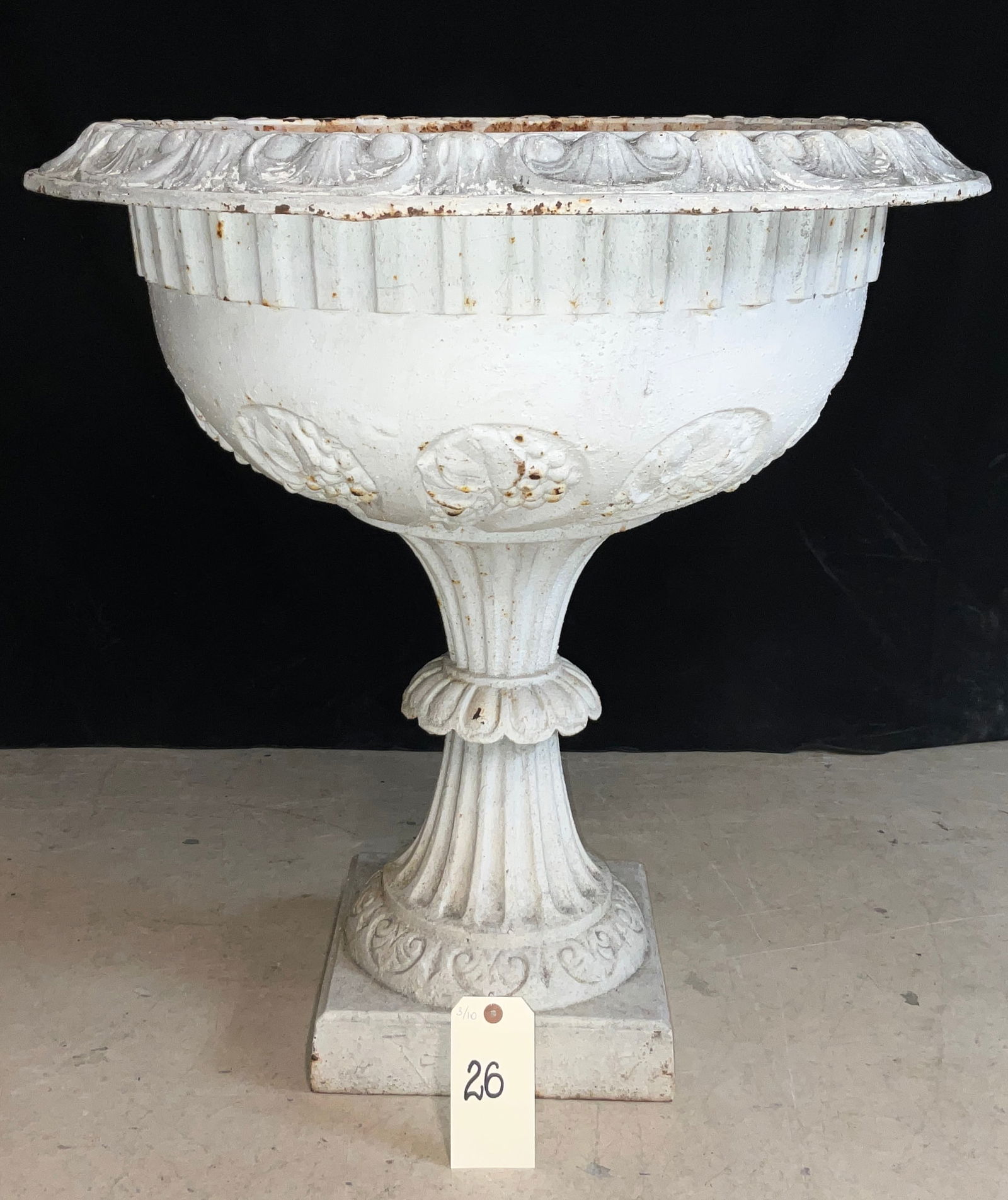 Neoclassical Style White Painted Cast Iron Garden Urn on Pedestal: This Neoclassical style cast-iron garden urn features a wide, flared rim decorated with scrolled acanthus motifs and a fluted neck. The rounded bowl is embellished with floral medallions and rests upo