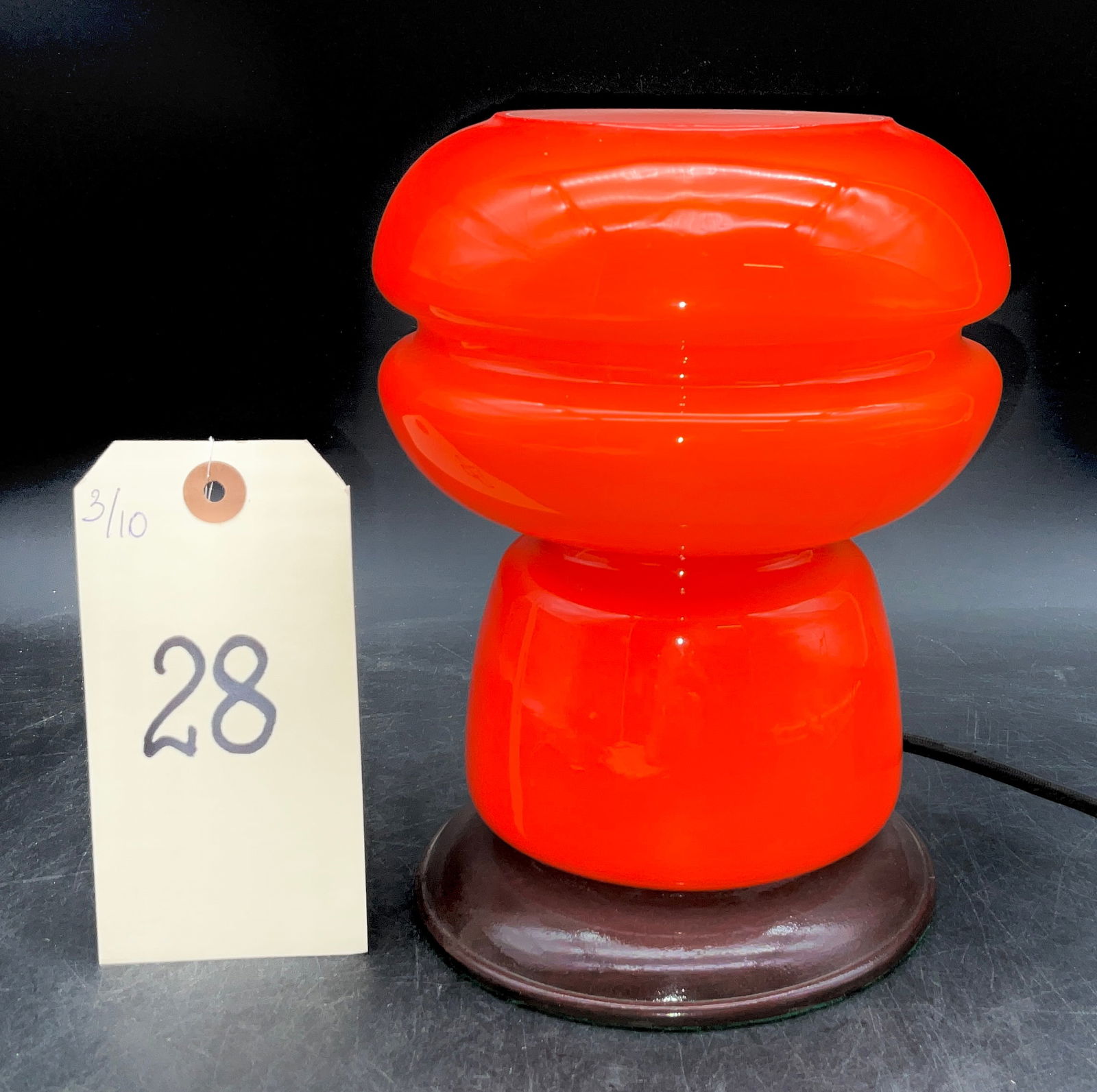 Mid-Century Modern Orange Cased Glass Table Lamp: This Mid-Century Modern table lamp features a vibrant orange cased glass body in a distinctive biomorphic, Space Age design. The two-tiered upper section rests on a tapered base, all supported by a da