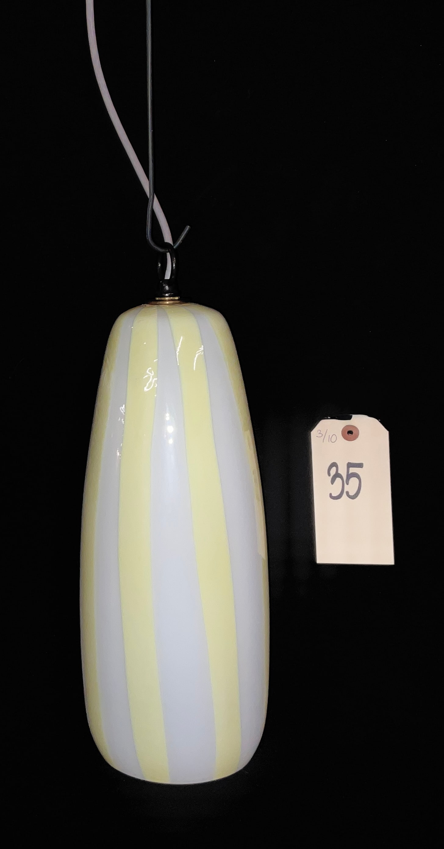 Venini Massimo Vignelli Mid-Century Modern Murano Glass Pendant Lamp: This Mid-Century Modern pendant lamp, designed by Massimo Vignelli for Venini, features an elongated capsule-shaped Murano glass shade with vertical stripes of opaque white and pale yellow. The fixtur