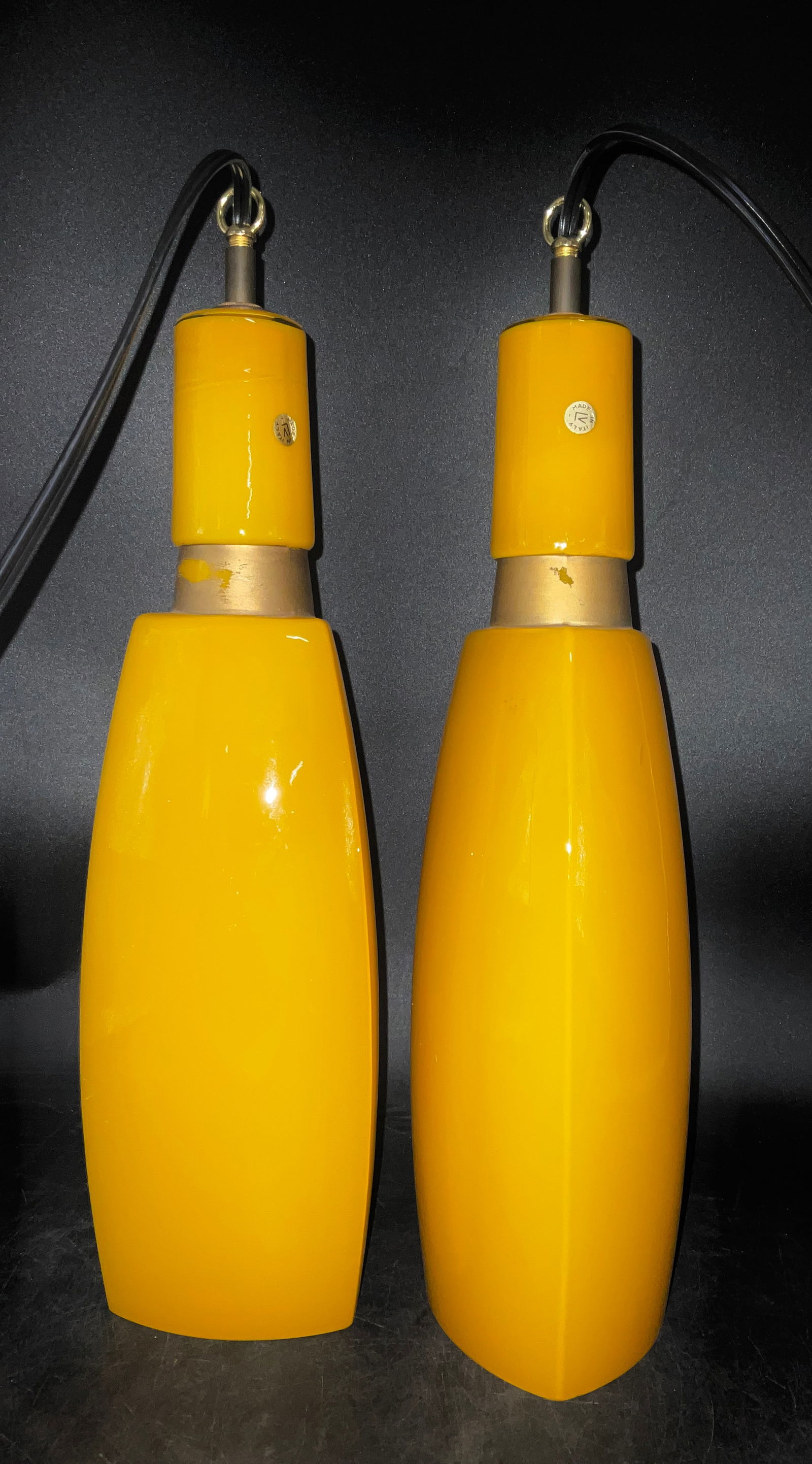 Vistosi Pair of Mid-Century Modern Yellow Cased Glass Bottle Pendant Lamps: This pair of Mid-Century Modern pendant lamps features elongated, two-part bottle-shaped shades crafted from vibrant yellow cased glass. Each shade is joined by a central brushed gold-tone metal band