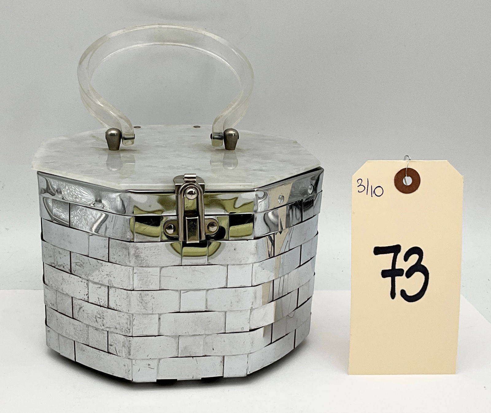 Mid-Century Modern Woven Metal and Lucite Box Purse, circa 1950s: This Mid-Century Modern octagonal box-style handbag possibly by Dorset Rex features a body of woven silver-toned metal strips over a black fabric foundation. The hinged lid is crafted from pearlescent