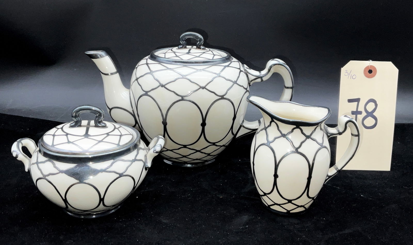 Lenox Art Nouveau Silver Overlay Porcelain Tea Service: This three-piece Lenox porcelain tea service includes a teapot, lidded sugar bowl, and creamer crafted in an elegant ivory-toned body. Each piece features a sophisticated silver overlay in a geometric