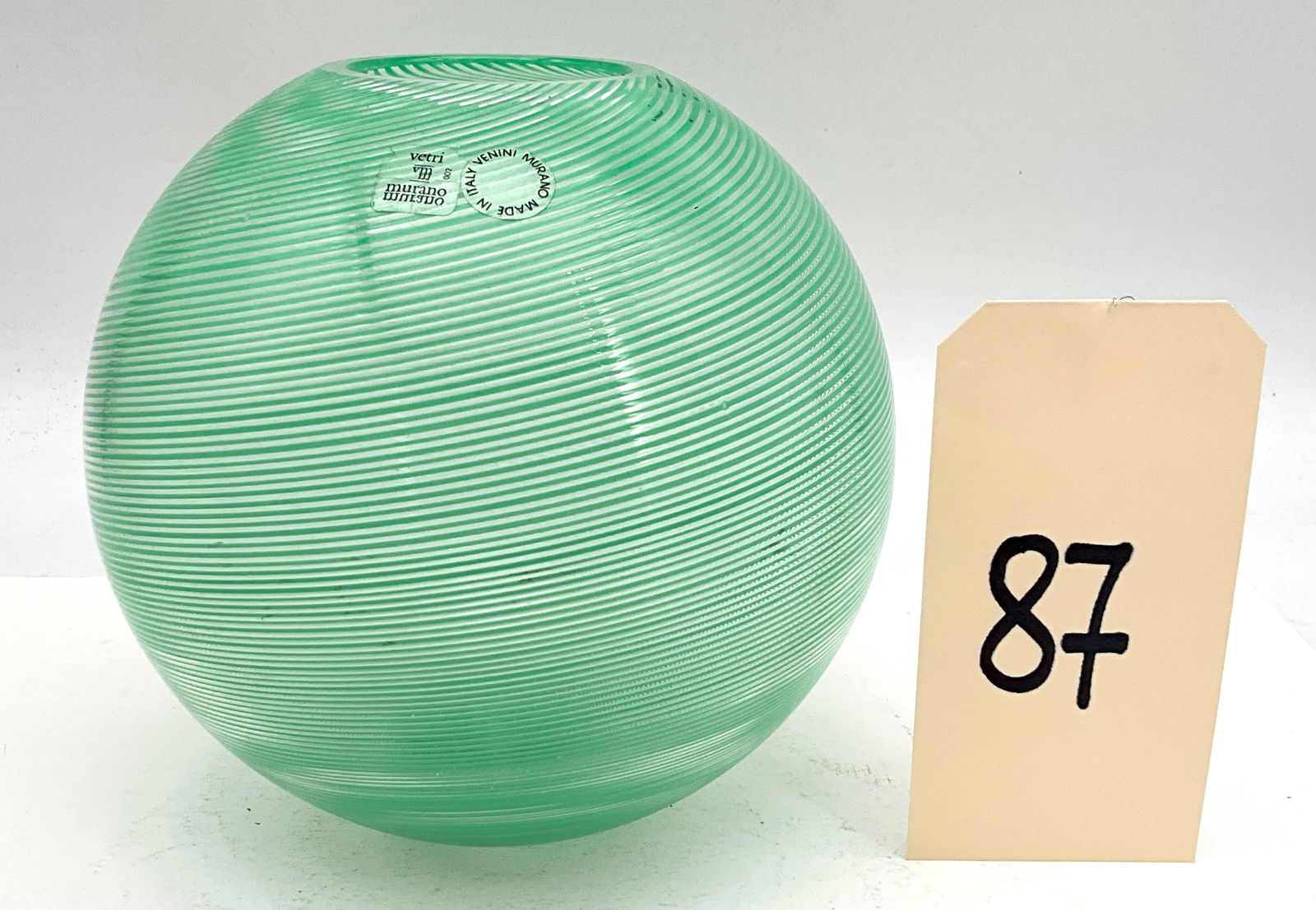 Venini Mezza Filigrana Art Glass Vase: This fine hand-blown glass vase by Venini is executed in the delicate mezza filigrana technique. The globular form features a continuous spiral of fine white canes embedded within a vibrant seafoam gr