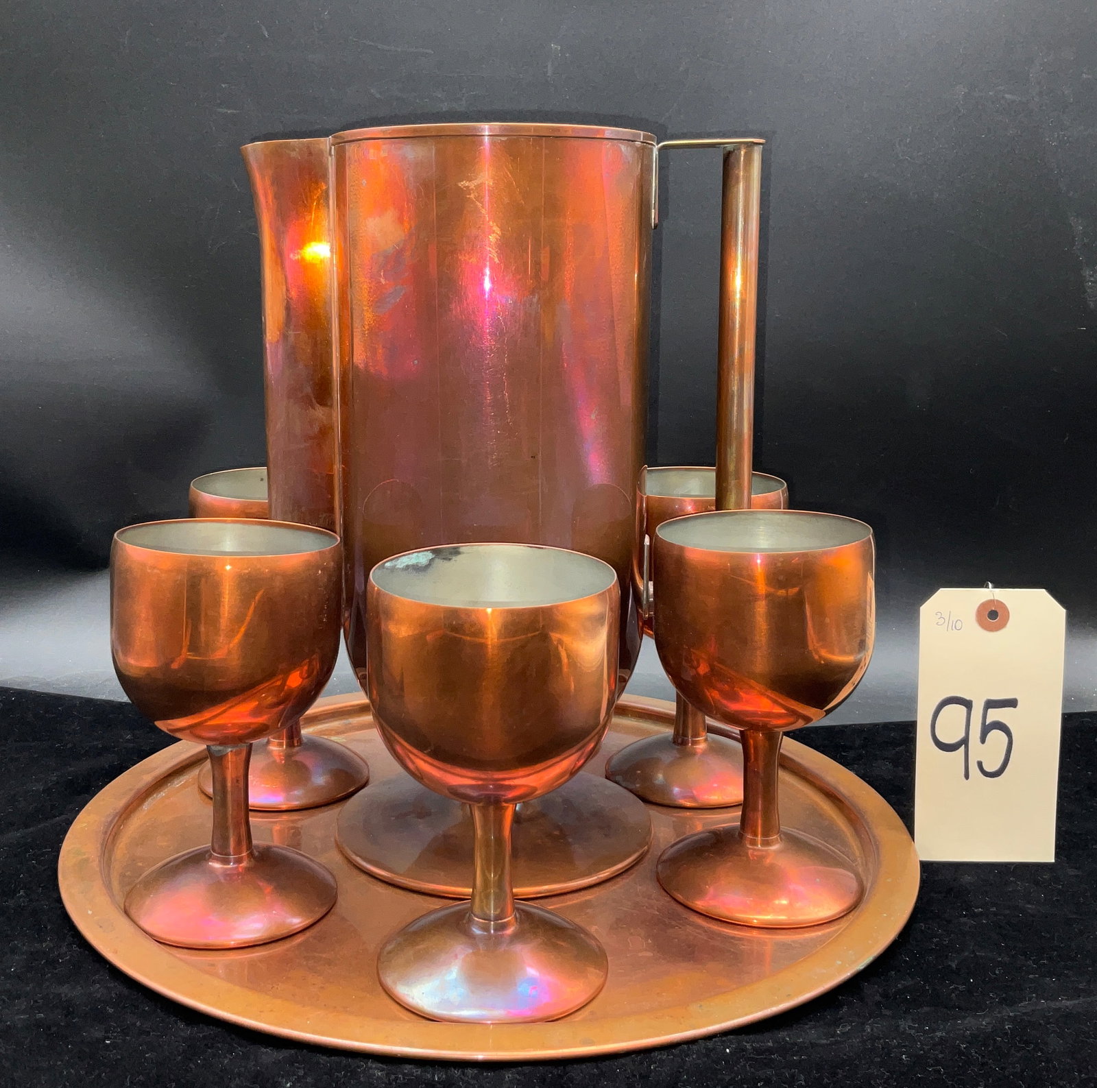 Vintage Eight-Piece Copper Beverage Service: This vintage eight-piece copper beverage service, likely designed by Norman Bel Geddes for Revere Copper and Brass, features the iconic Art Deco Baron pattern. The set includes a tall cylindrical pitc