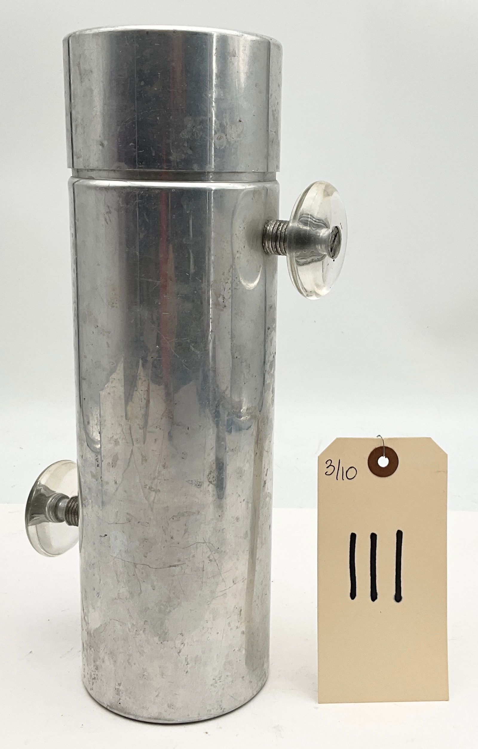 Kromex Konga Mid-Century Modern Aluminum Cocktail Shaker with Clear Knobs: This vintage Kromex Konga cocktail shaker features a sleek industrial Art Deco design crafted from polished aluminum. The cylindrical body is equipped with two clear screw-in knobs on the sides and a