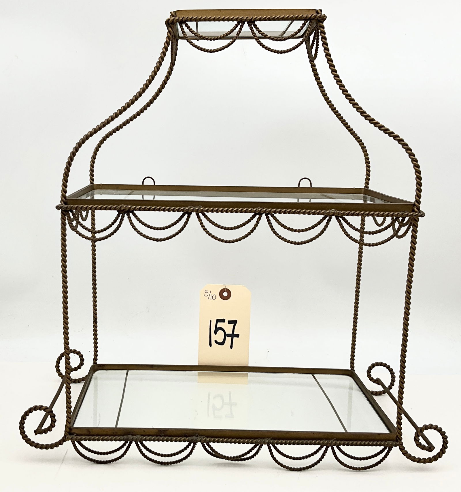 Italian Gilt Iron Rope and Tassel Three-Tier Hollywood Regency Display Shelf: This vintage Hollywood Regency style display shelf features a twisted gilt iron frame designed to resemble rope with decorative hanging swags. The three-tier unit includes clear glass inset shelves an