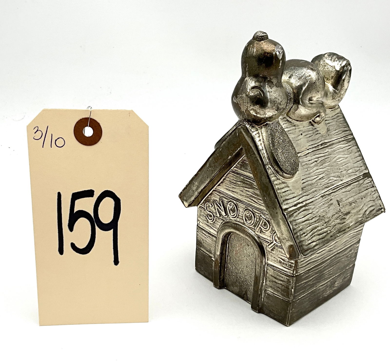 Vintage Leonard Silverplate Peanuts Snoopy Doghouse Coin Bank: This vintage silver-plated cast metal coin bank by Leonard depicts the Peanuts character Snoopy reclining atop a textured wood-grain doghouse. The underside is marked with a cursive Leonard hallmark a