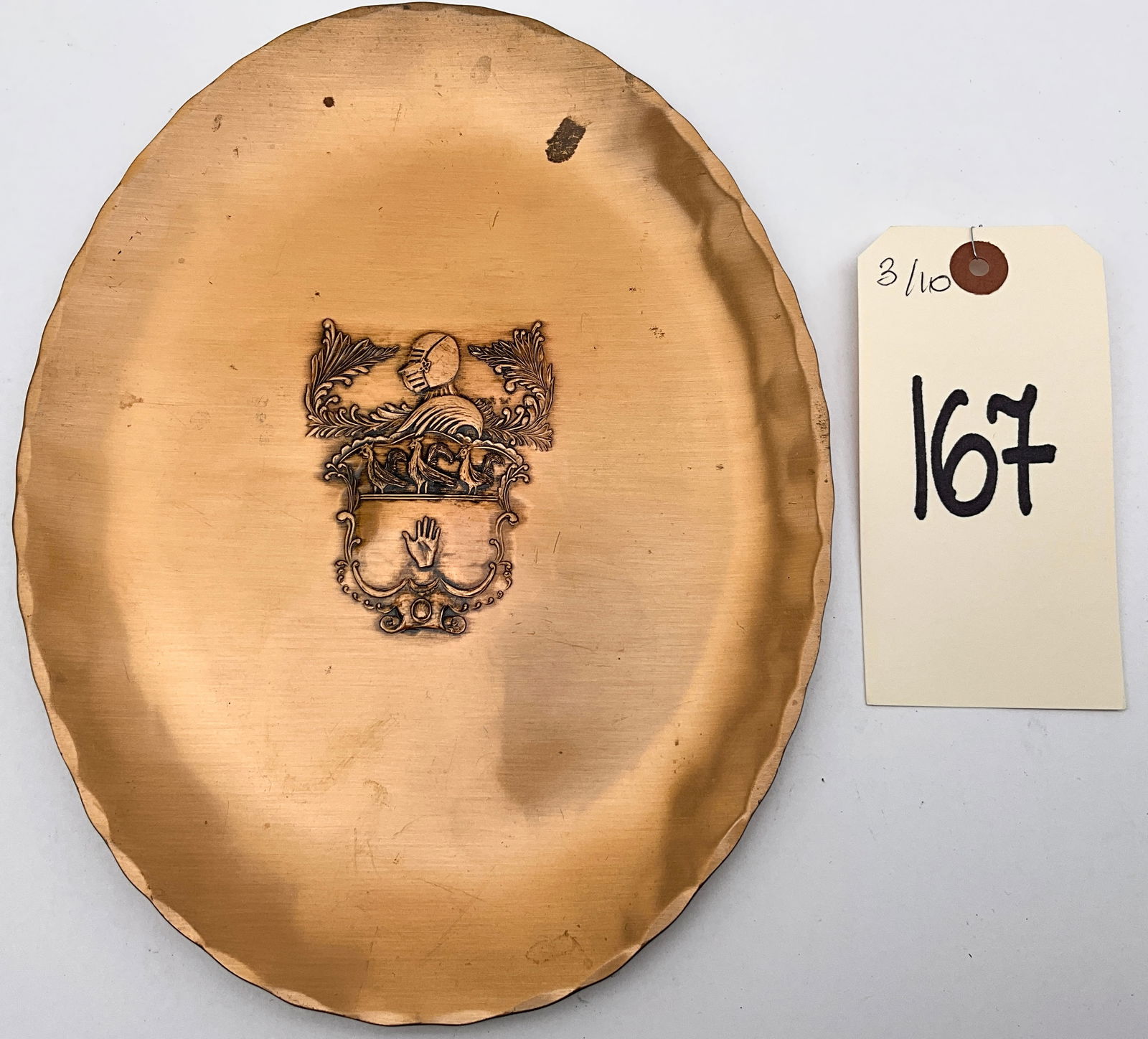 Natale Hand-Made Bronze Armorial Platter: This mid-century oval platter is hand-crafted from bronze by Natale of Leesburg, Pennsylvania. The piece features a scalloped, fluted rim and a central etched armorial crest depicting a knight's helme