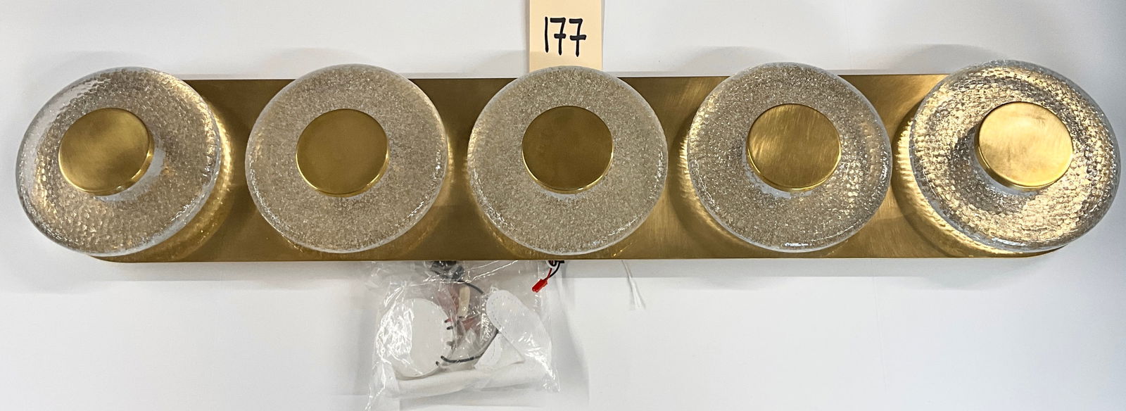 Corbett Lighting Pearl Collection Five-Light Vanity Sconce in Vintage Brass: This modern five-light vanity wall sconce from the Corbett Lighting Pearl collection features a long oval backplate in a brushed vintage brass finish. The fixture is adorned with five circular diffuse