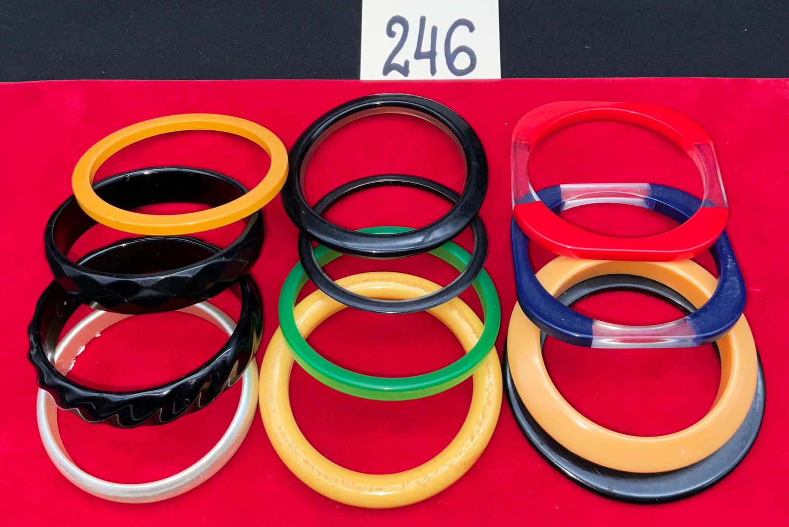 Bakelite and Vintage Plastic Bangle Bracelets, Stackable Multi-Color Collection: This collection features twelve stackable slip-on bangles crafted from Bakelite and vintage resins in a vibrant palette of black, red, yellow, green, and cream. The assortment includes diverse
