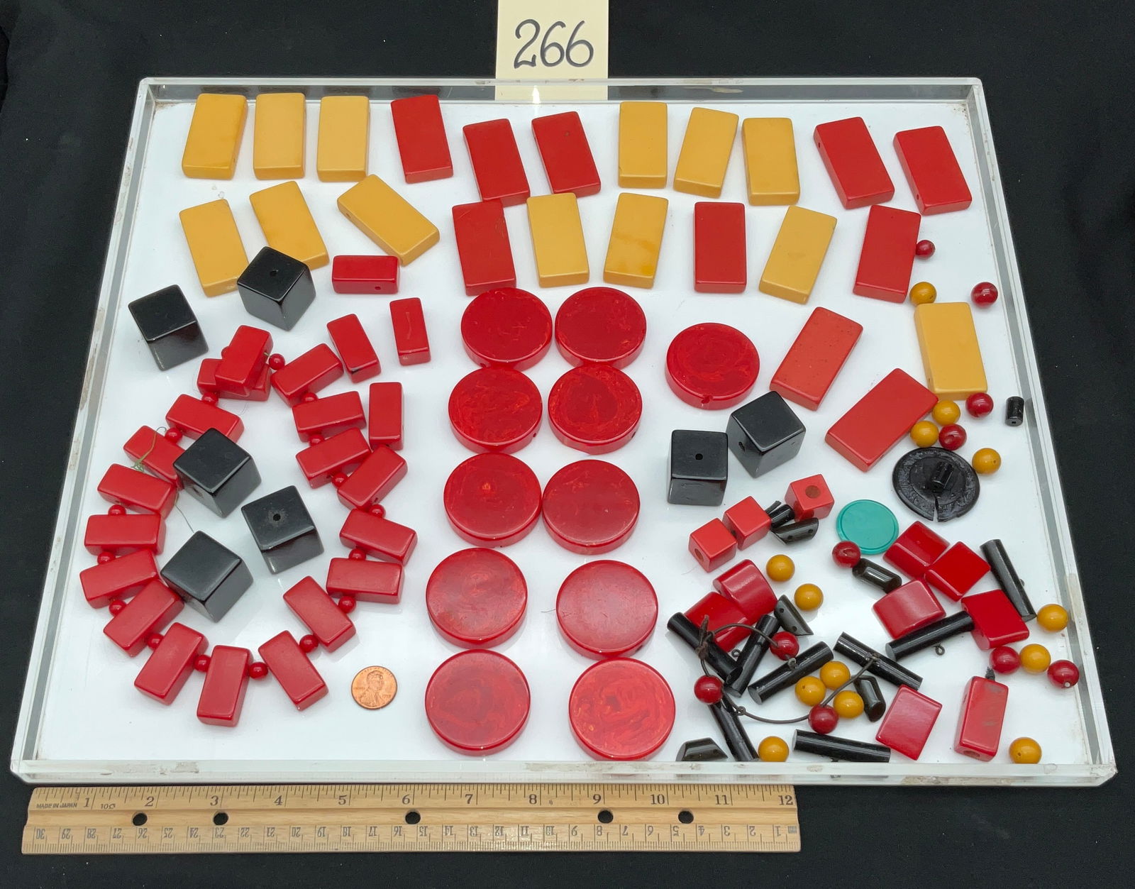 Bakelite Jewelry Components and Partially Assembled Necklace: This collection consists of various vintage Bakelite components and a partially assembled necklace in shades of red, butterscotch yellow, and black. The assortment includes geometric shapes such as la