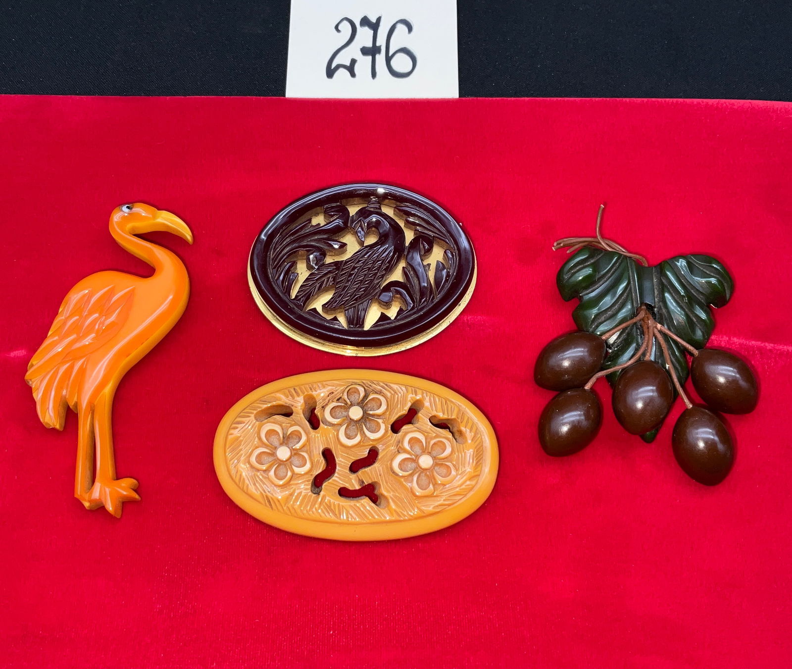 Gold-Toned Metal and Carved Bakelite Pins, Collection of Four Figural and Floral Brooches: This collection features four vintage costume jewelry brooches crafted from carved Bakelite in various colors and styles. The group includes a stylized orange wading bird, a reticulated burgundy bird