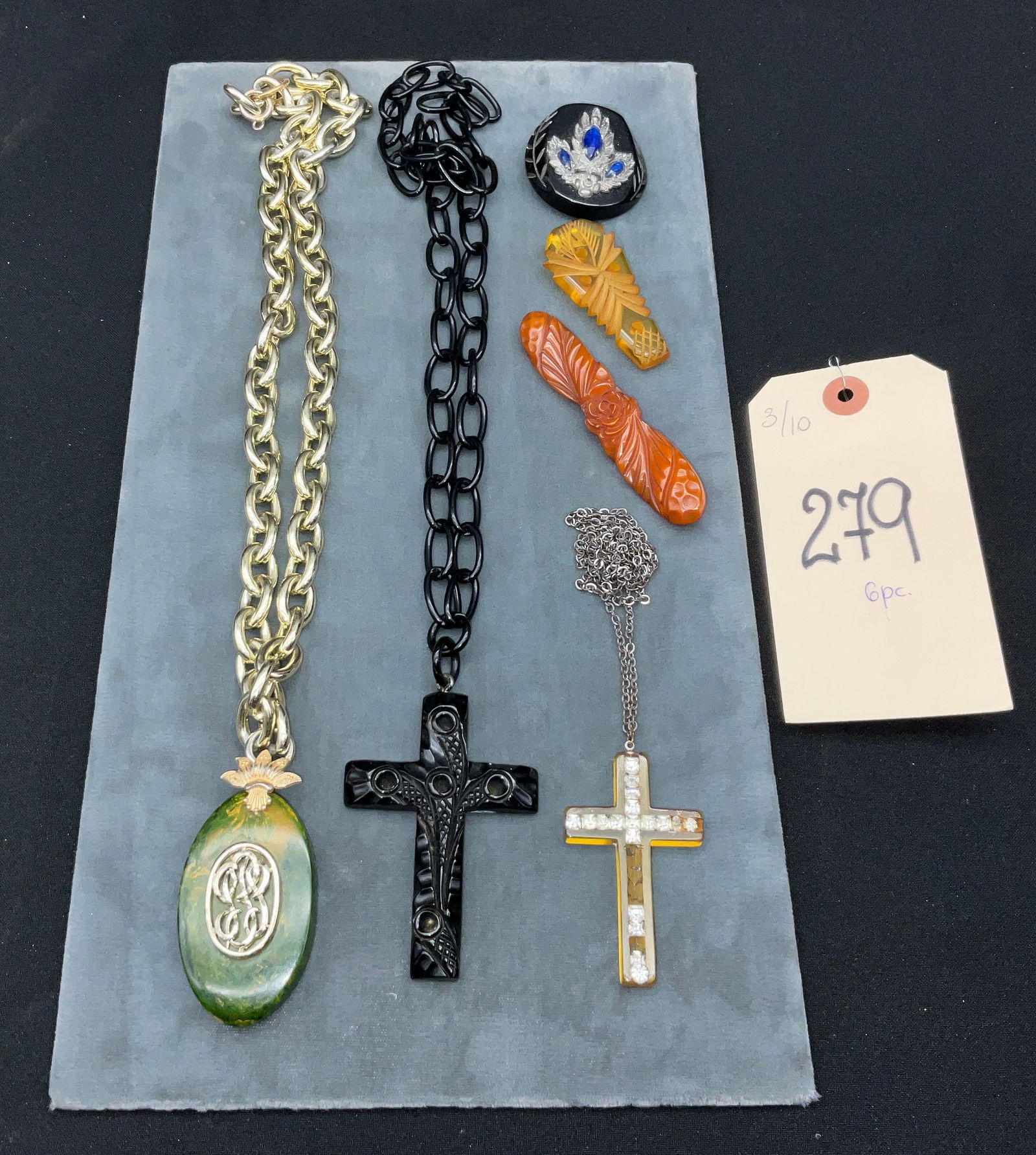 Vintage Costume Jewelry Collection featuring Bakelite and Vulcanite Style Pendants and Brooches: This curated collection features an assortment of vintage costume jewelry, including three necklaces, two brooches, and a dress clip primarily composed of early plastics such as Bakelite and celluloid
