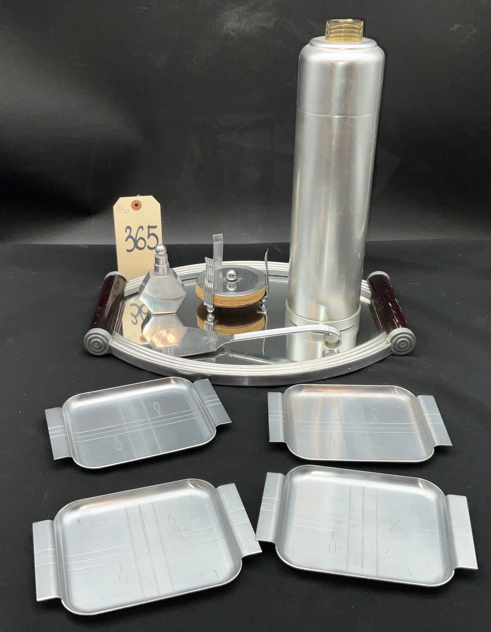 Art Deco Aluminum Barware Collection with Manhattan Style Shaker and Revere Plates: This collection of Art Deco barware features a tall brushed aluminum cocktail shaker by Kensington in the Manhattan style and an oval mirrored tray with dark scroll-form handles. The assembly includes