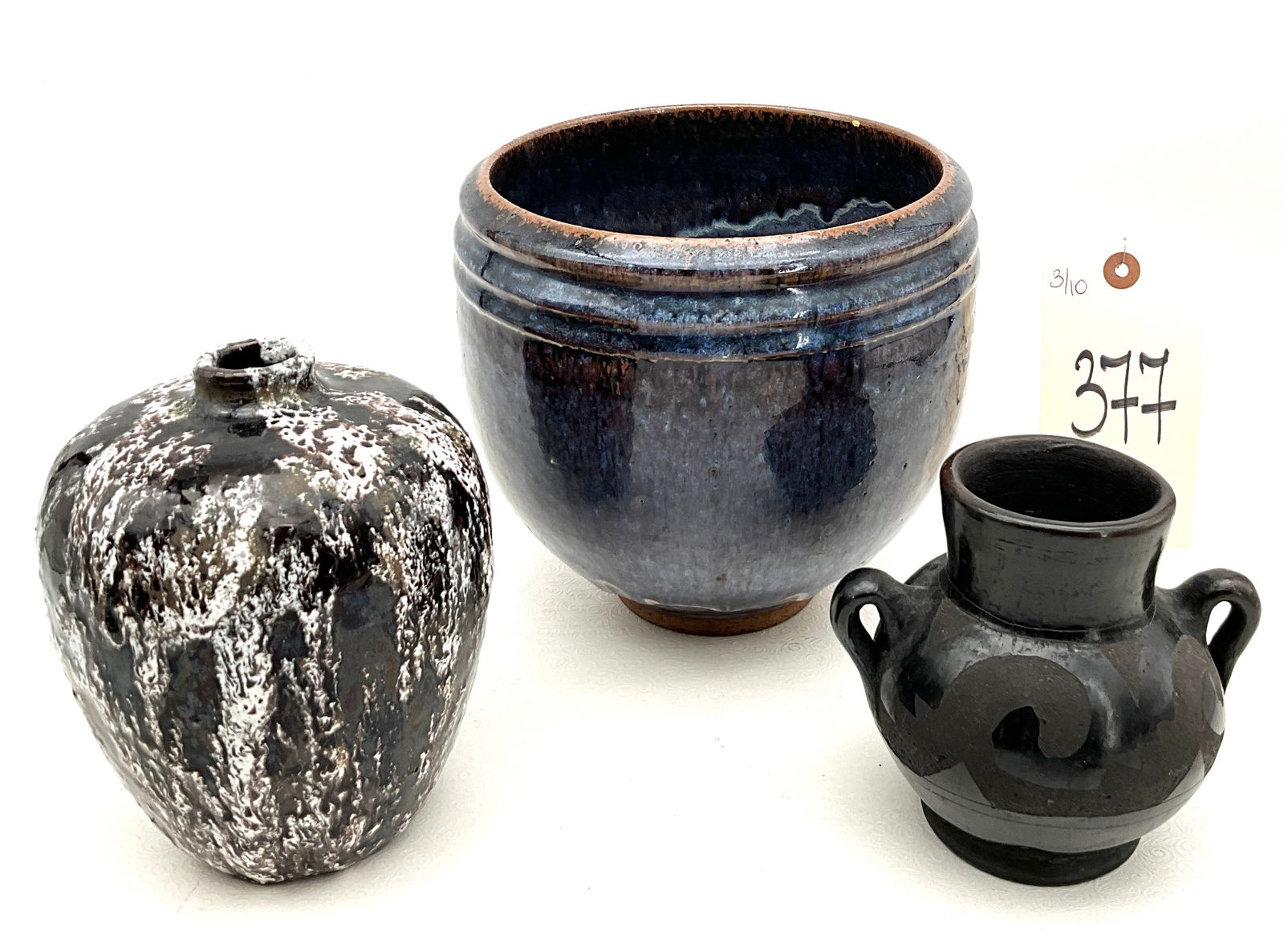 Miller and Fredley Studio Art Pottery Vessels: This lot includes a large stoneware bowl with a cobalt and purple drip glaze signed Miller, a mottled black and white vase signed Fredley, and an unmarked matte black twin-handled pot. The blue bowl f