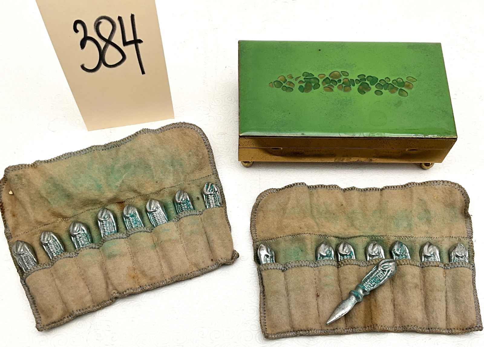 Unmarked Vintage Corn Cob Holders and Decorative Trinket Box, Mid-Century Era: This vintage group includes sixteen cast metal corn cob holders and a decorative enameled metal box measuring 5"X3.25"X1.25". The unmarked gold-toned box features a green enameled lid with organic mot