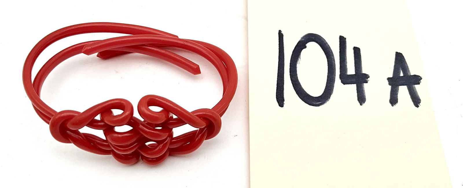 Vintage 1930s Celluloid Bangle Bracelet with Knotted Design: This vintage 1930s celluloid bracelet features a vibrant lipstick red color and a striking wrap-around design. The focal point showcases an intricate multi-strand knotted motif that transitions into p