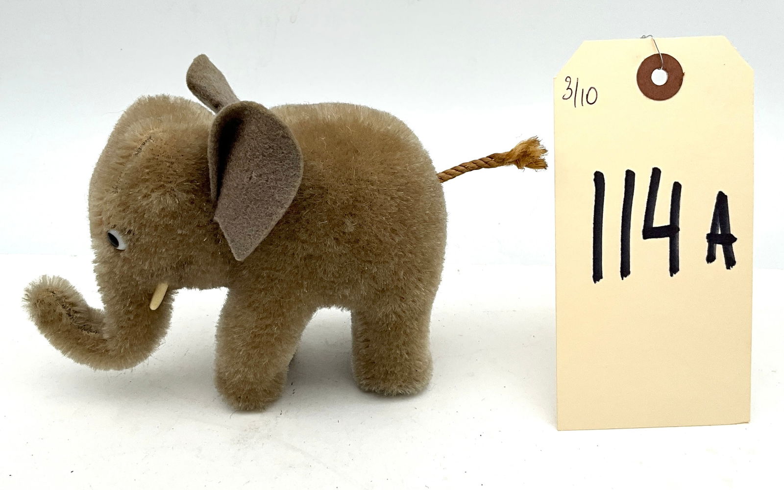 Attributed to Steiff, Art Deco Style Plush Elephant, mid-20th Century: This plush elephant is attributed to Steiff and reflects an Art Deco influence in its stylized form. The static figure is crafted from light brown fuzzy plush material with felt ears and a twisted cor