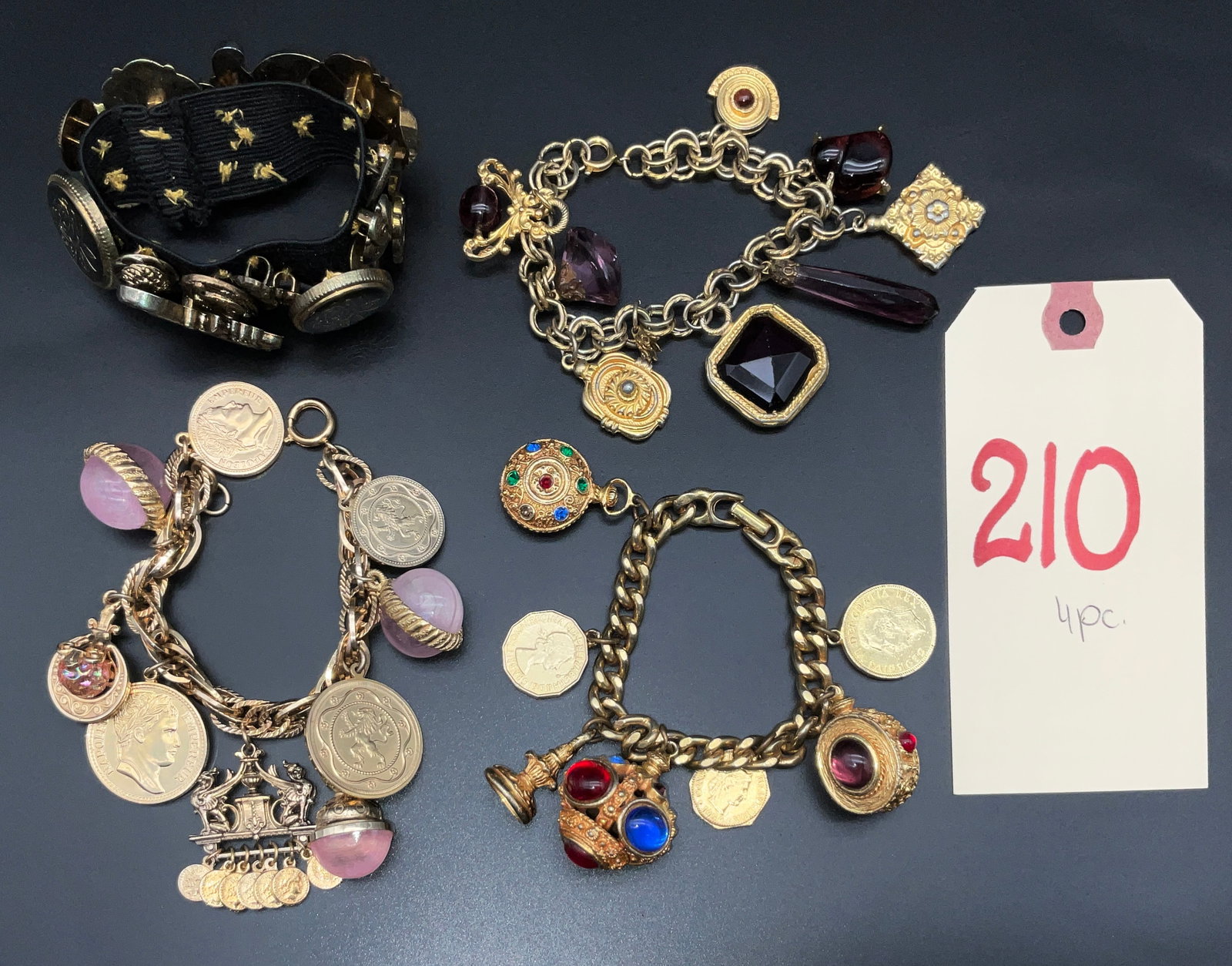 A Collection of Four Vintage Gold-Tone Costume Jewelry Charm and Button Bracelets: This four-piece collection of vintage costume jewelry includes three multi-charm link bracelets and one stretch cuff. The link bracelets feature gold-tone metal chains adorned with various elements