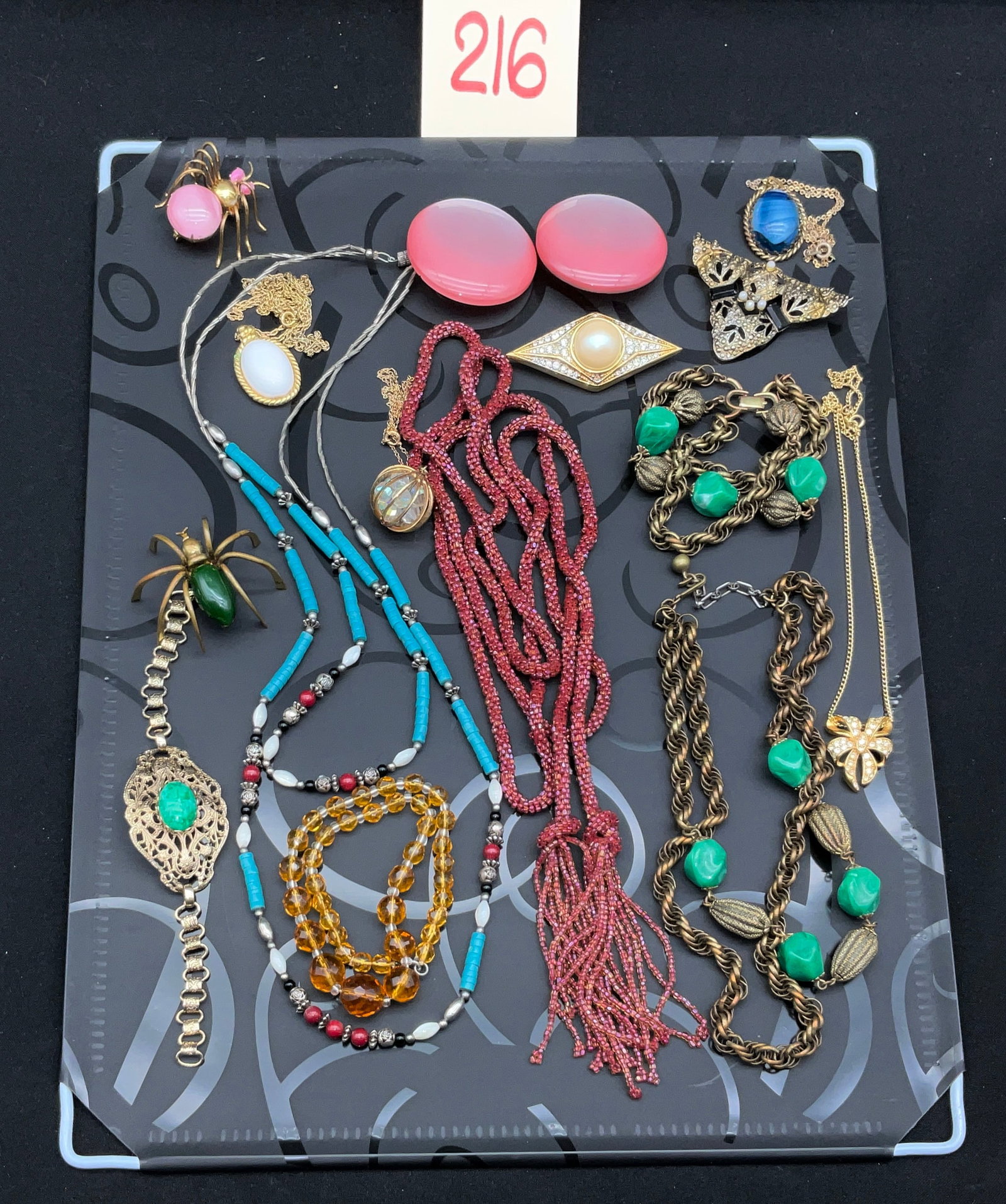 A Collection of Vintage Costume Jewelry Including Signed Trifari Necklace: This assortment of vintage costume jewelry features a gold-tone Trifari bow necklace accented with clear rhinestones and a stamped maker's mark. The collection includes two large figural spider brooch