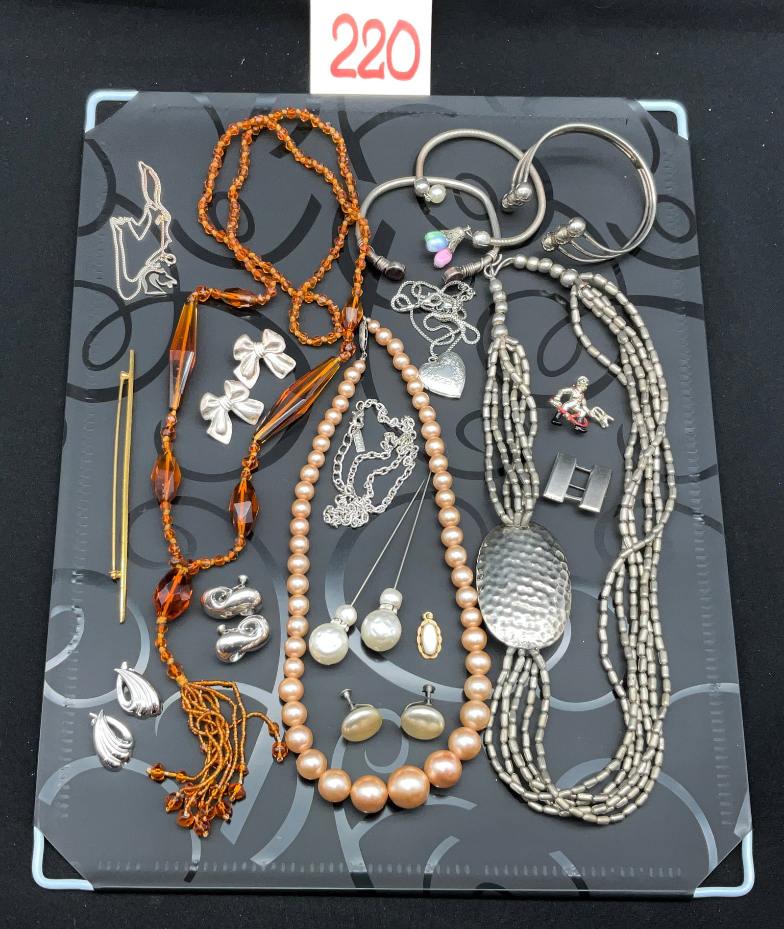 A Collection of Vintage and Modern Costume Jewelry: This assortment of wearable jewelry includes a single-strand graduated faux pearl necklace and a silver-tone multi-strand necklace featuring a large hammered metal focal pendant. Multiple pieces are