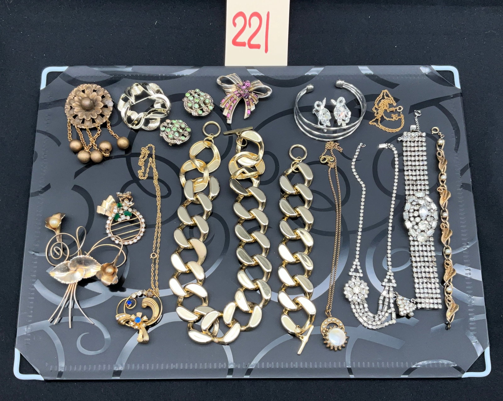An Assortment of Eighteen Vintage Costume Jewelry Pieces: This collection of eighteen assorted vintage costume jewelry pieces includes necklaces, brooches, bracelets, and earrings in mid-century and modern styles. A prominent piece is a gold-tone scrolled