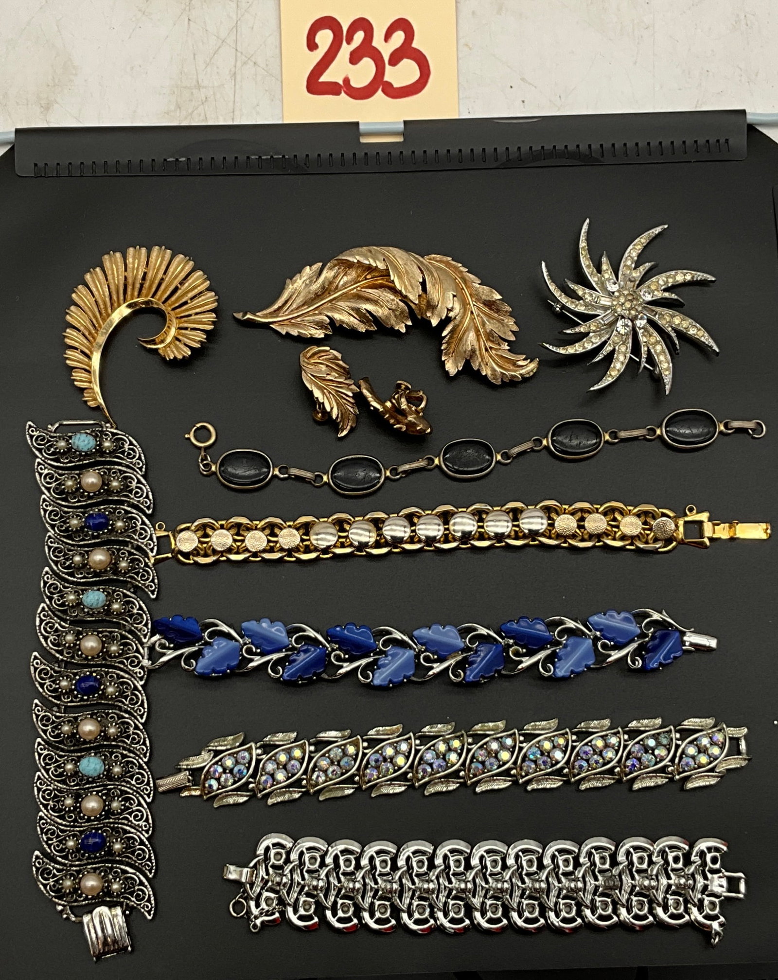 An Assortment of Ten Mid-Century Costume Jewelry Pieces: This assortment of ten mid-century costume jewelry pieces includes four brooches, five bracelets, and one pair of clip-on earrings featuring signed items by Trifari and Coro. Construction materials