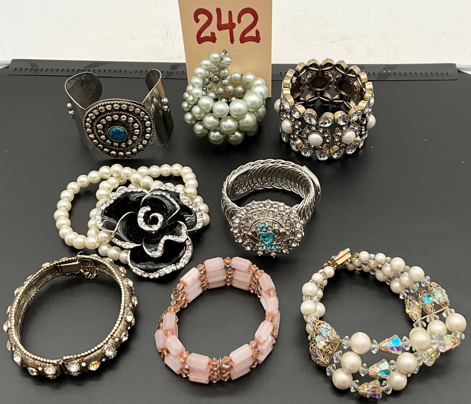 Eight Assorted Contemporary and Vintage Style Costume Jewelry Bracelets: This lot consists of eight assorted bracelets including a wide antiqued silver-tone cuff with a blue cabochon and various faux pearl stretch designs. Notable pieces include a large black enamel rose