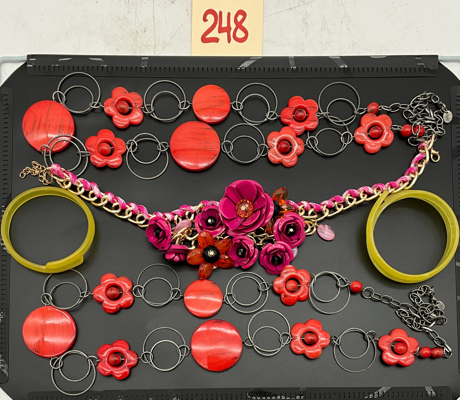 A Lot of Five Pieces of Costume Jewelry Including Kate Spade Rosy Posies: An assortment of five pieces of costume jewelry includes a Kate Spade Rosy Posies statement necklace, two Claire's necklaces, and two bangles. The chunky bib-style necklace features a gold-tone chain 