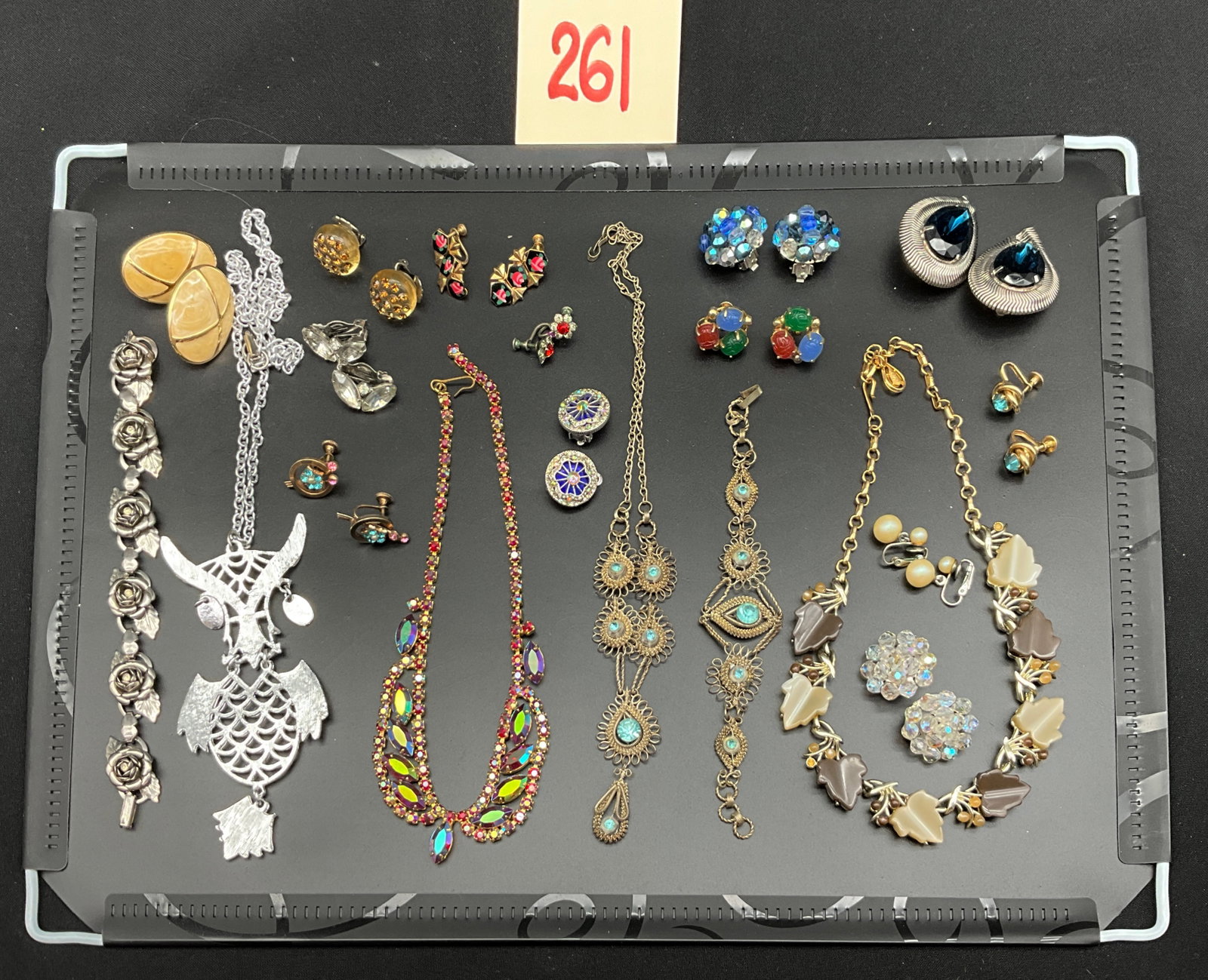 An Assortment of Vintage Rhinestone and Thermoset Costume Jewelry: This collection of mid-century costume jewelry features a diverse range of styles including a large articulated silver-tone owl pendant and a matching silver-tone wirework necklace and bracelet set